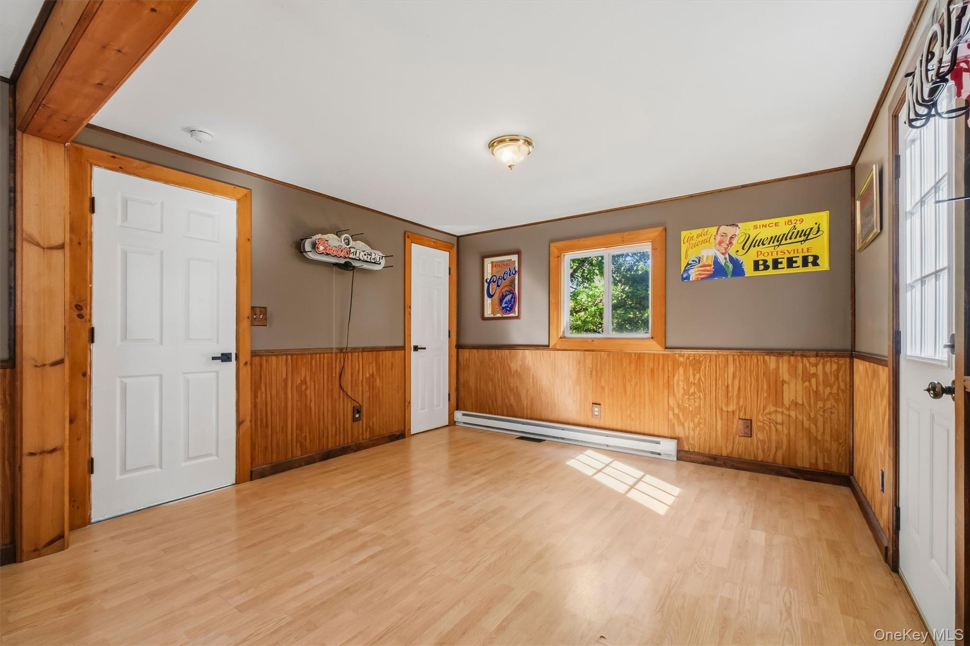 Wood-finish flooring with natural light, a window with wood trim, and a ceiling-mounted light fixture