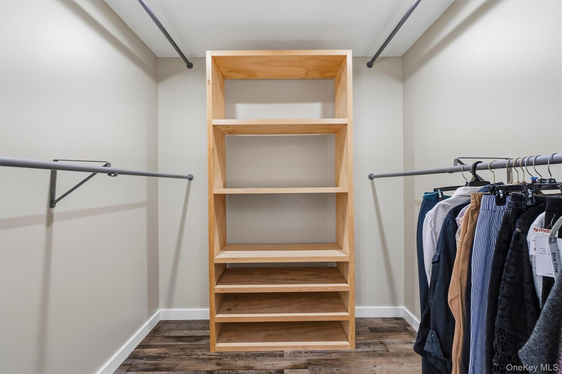 Walk-in closet featuring wood-finish flooring, built-in shelving, and multiple clothing rods