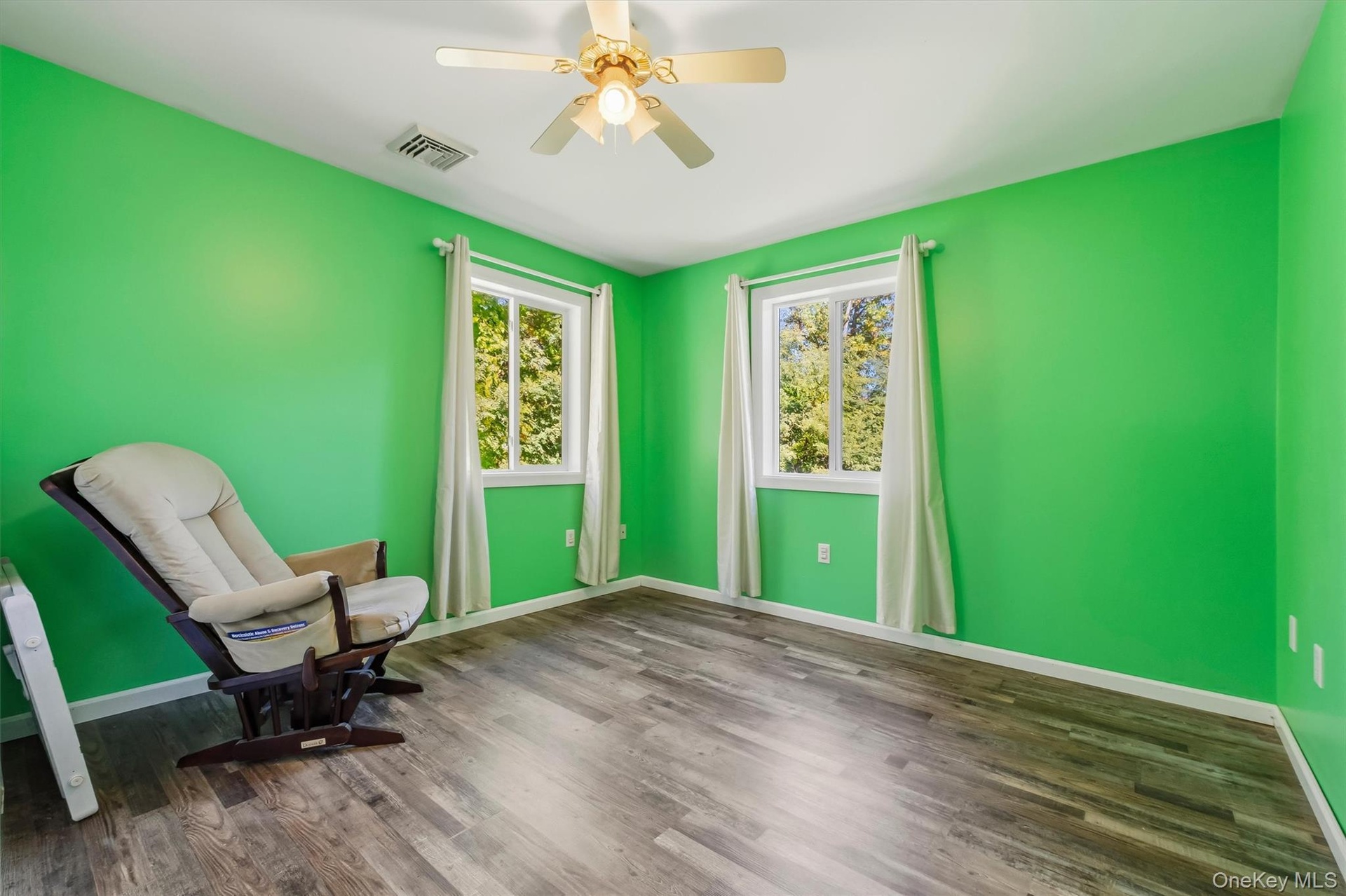 Bedroom 3 featuring wood-finish flooring, two windows, and a ceiling fan with integrated lighting
