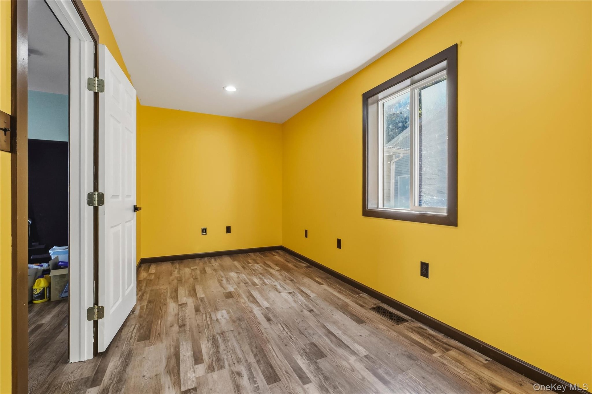 Office with Wood-finish flooring, recessed ceiling lighting, and a single window with dark trim