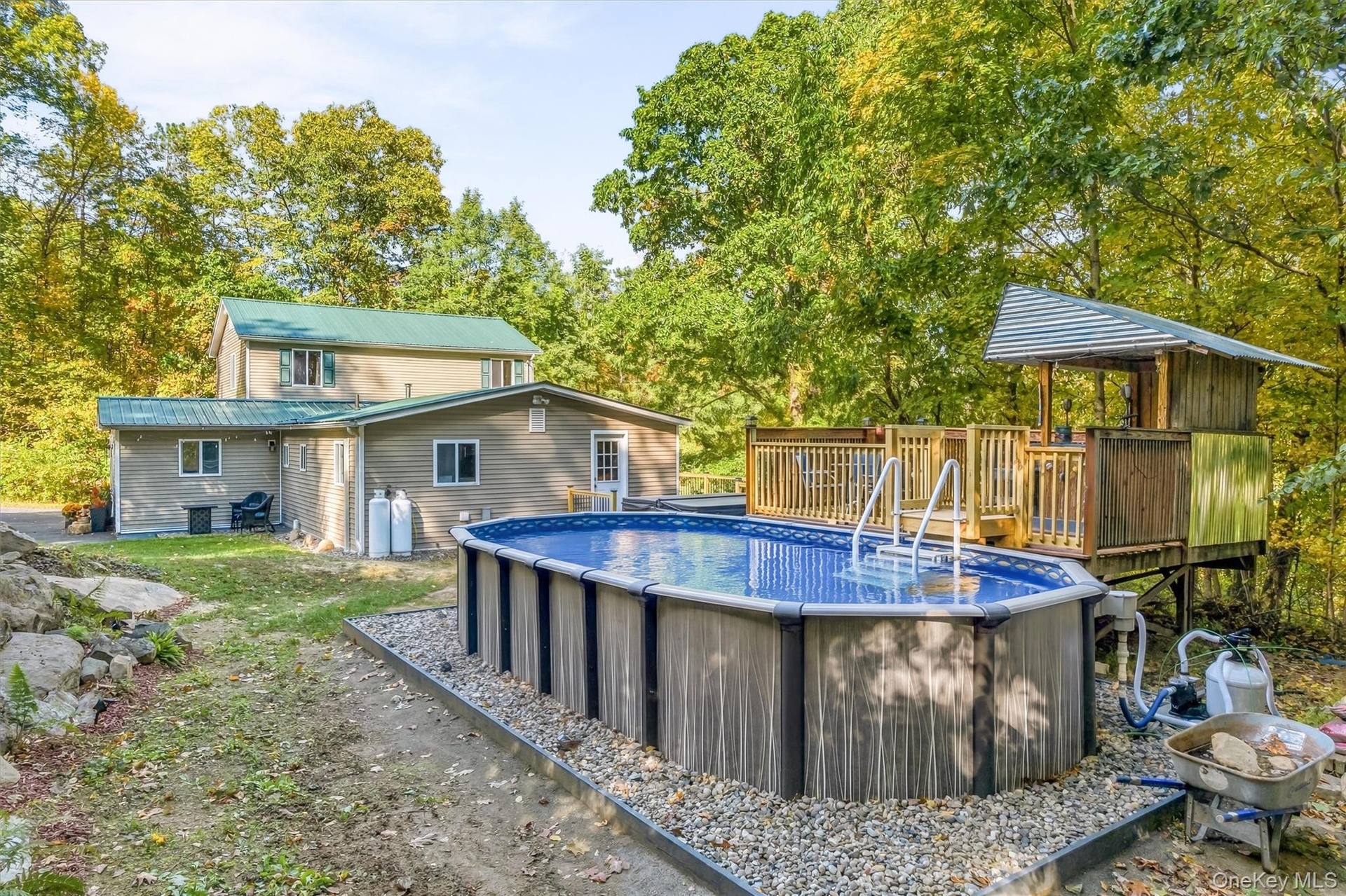 Above-ground pool with surrounding gravel, multi-level wooden deck, and elevated wooden structure
