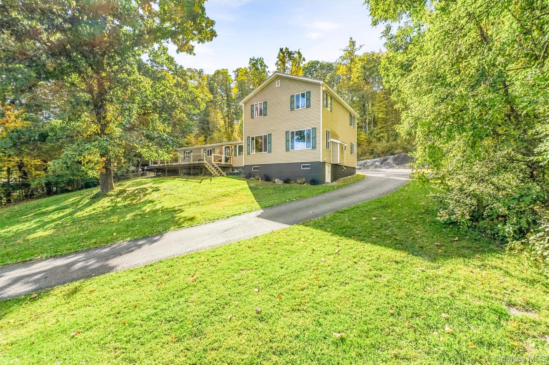 Two-story residence with siding exterior, green window shutters, and a sloped asphalt driveway