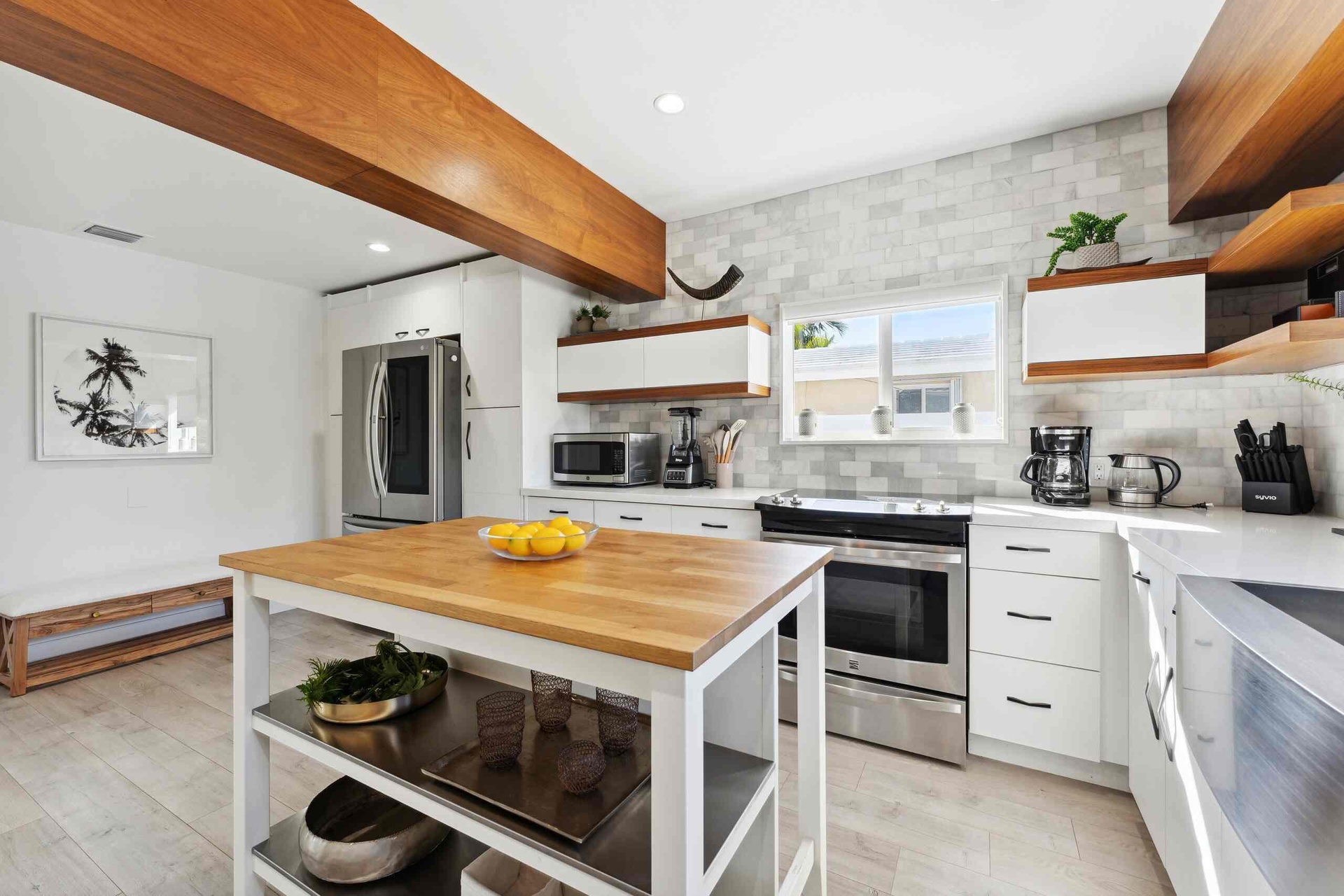 Contemporary kitchen featuring white cabinetry, stainless steel appliances, a butcher block island, light wood-finish flooring, and a subway tile back