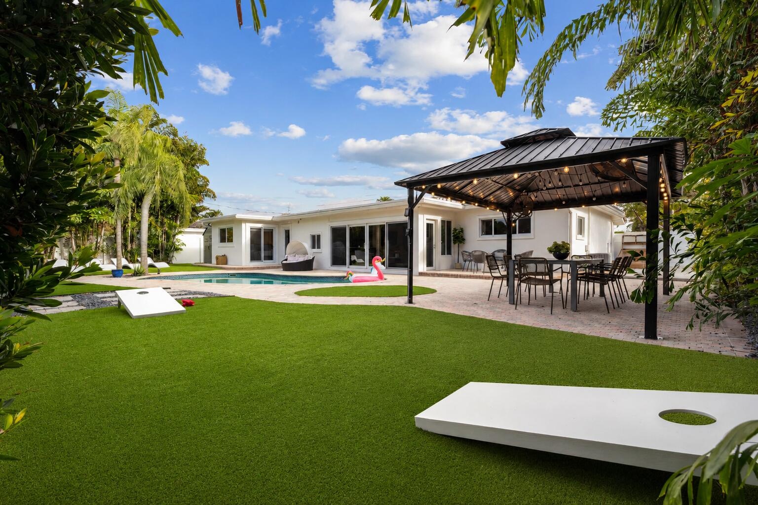 Expansive backyard featuring a manicured lawn, mature landscape plantings, and a modern pergola structure with integrated seating area