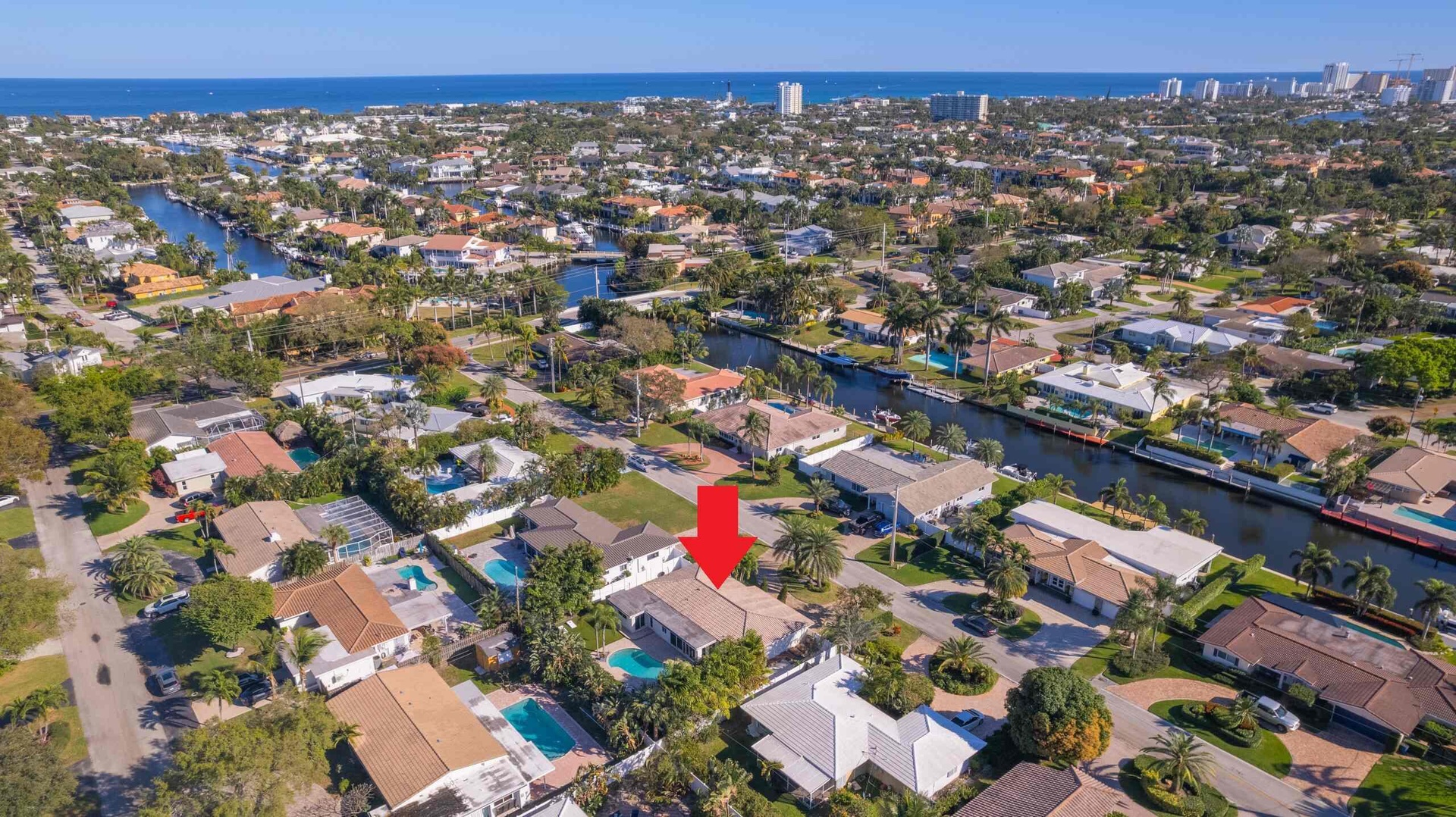 Aerial perspective of a neighborhood featuring residential properties, waterways, and distant coastal waters