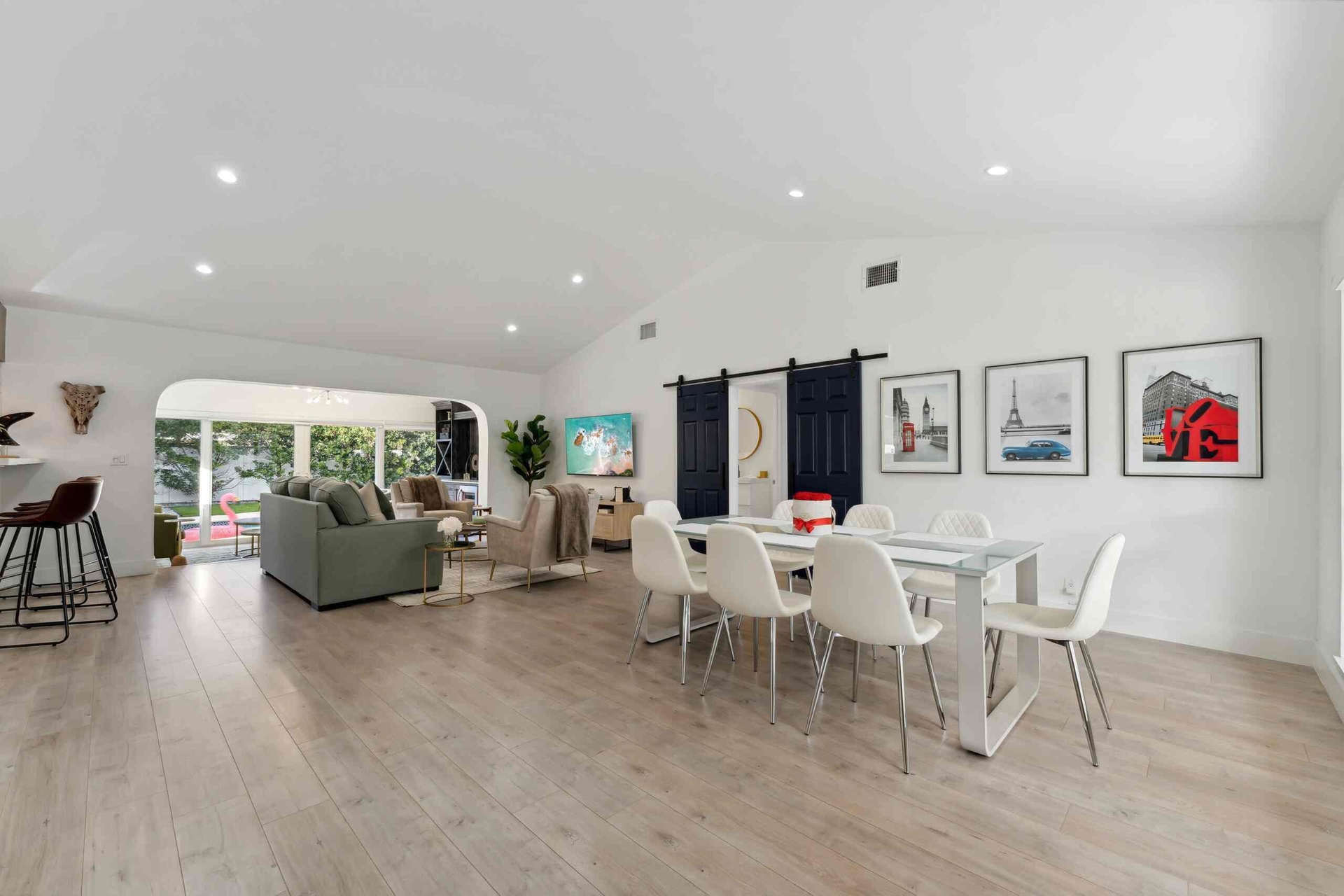 Open-concept living space showcasing wood-finish flooring, recessed ceiling lighting, and abundant natural light from large windows