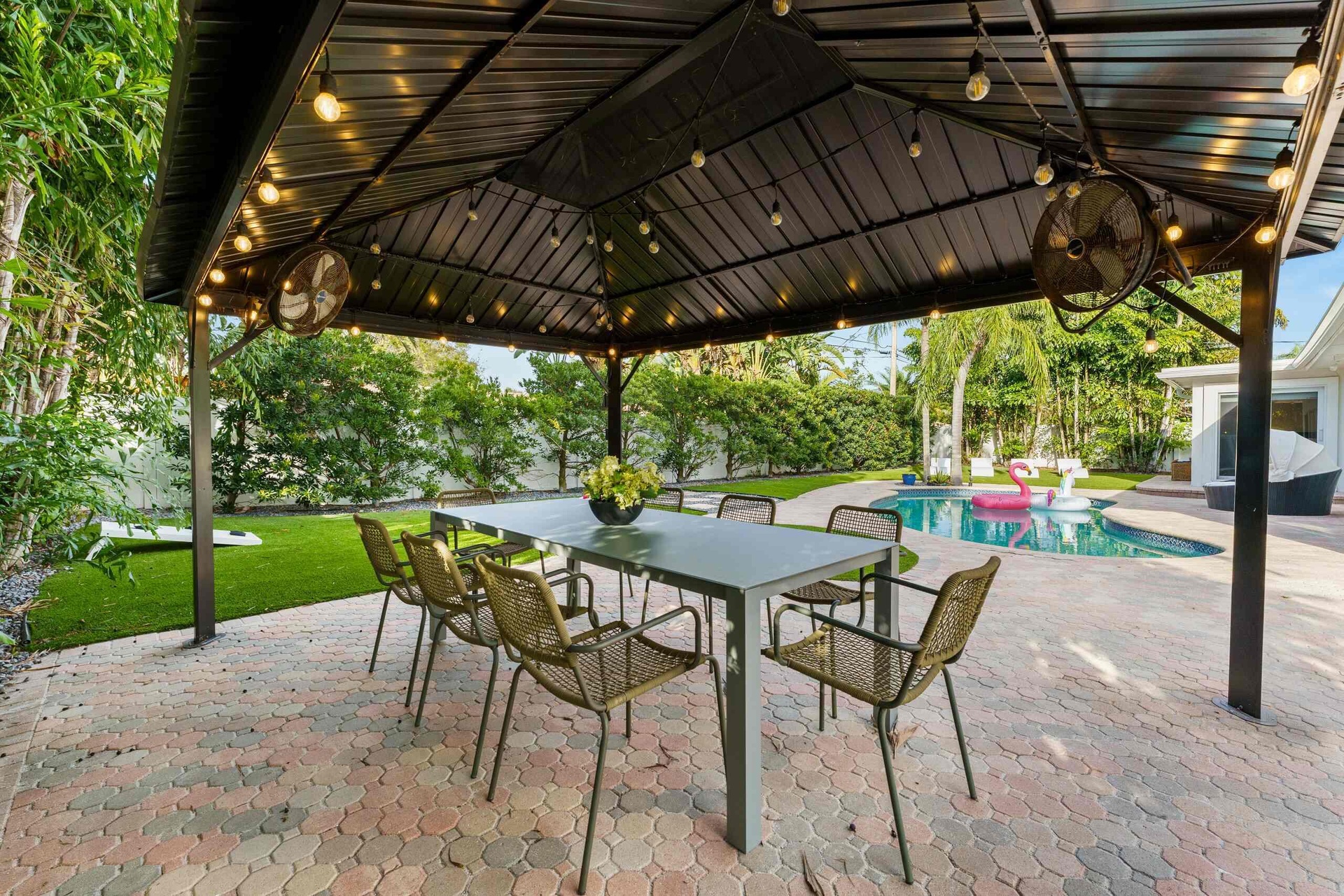Sophisticated outdoor entertaining space featuring a sturdy metal pergola with integrated overhead lighting and ceiling fans, anchored by a spacious d