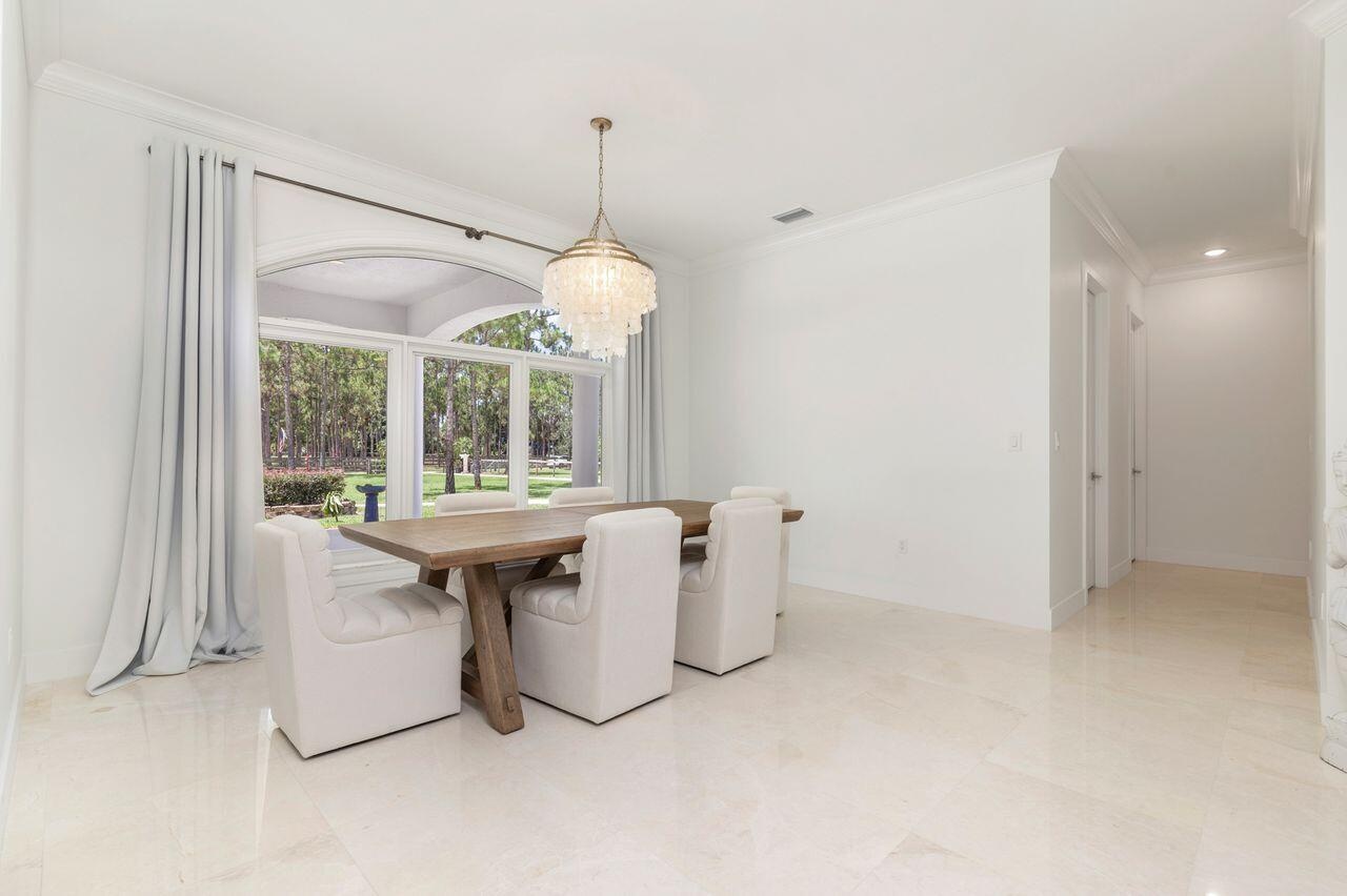 Bright interior space featuring large arched windows, crown molding, a decorative chandelier.