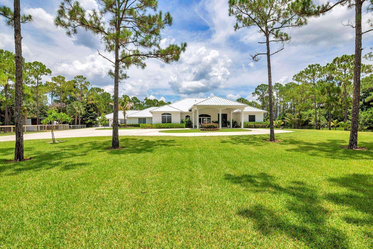 Spacious front lawn with mature trees and a circular driveway