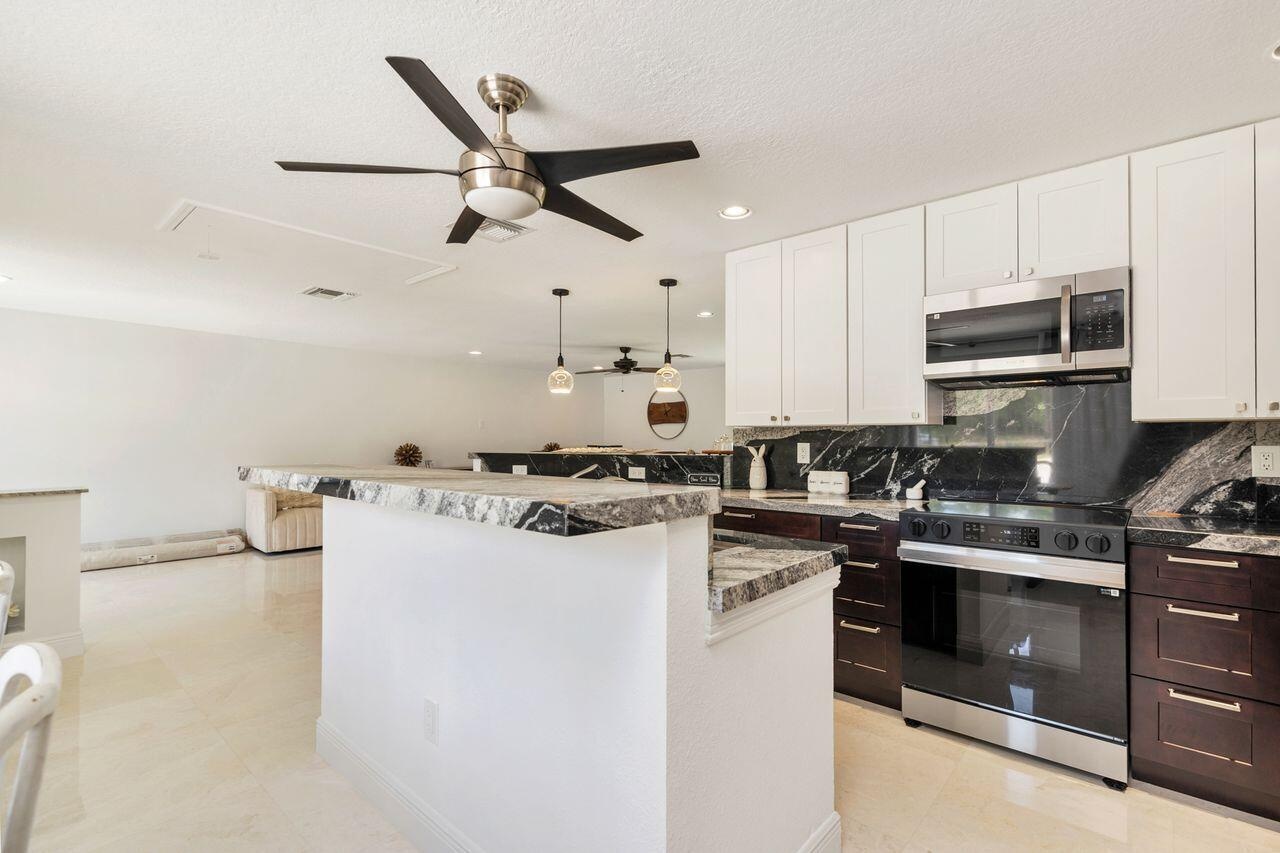 Kitchen featuring white upper cabinetry, dark lower cabinetry, stainless steel appliances, and contrasting countertops with backsplash
