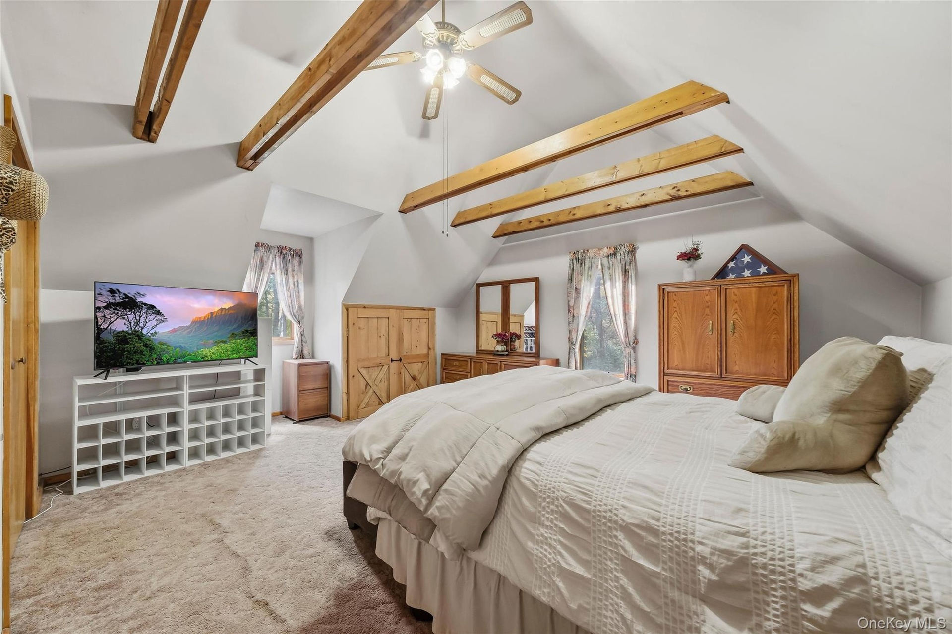The primary bedroom is such an intimate space with vaulted ceilings, exposed beams and a knee wall closet with barn doors.