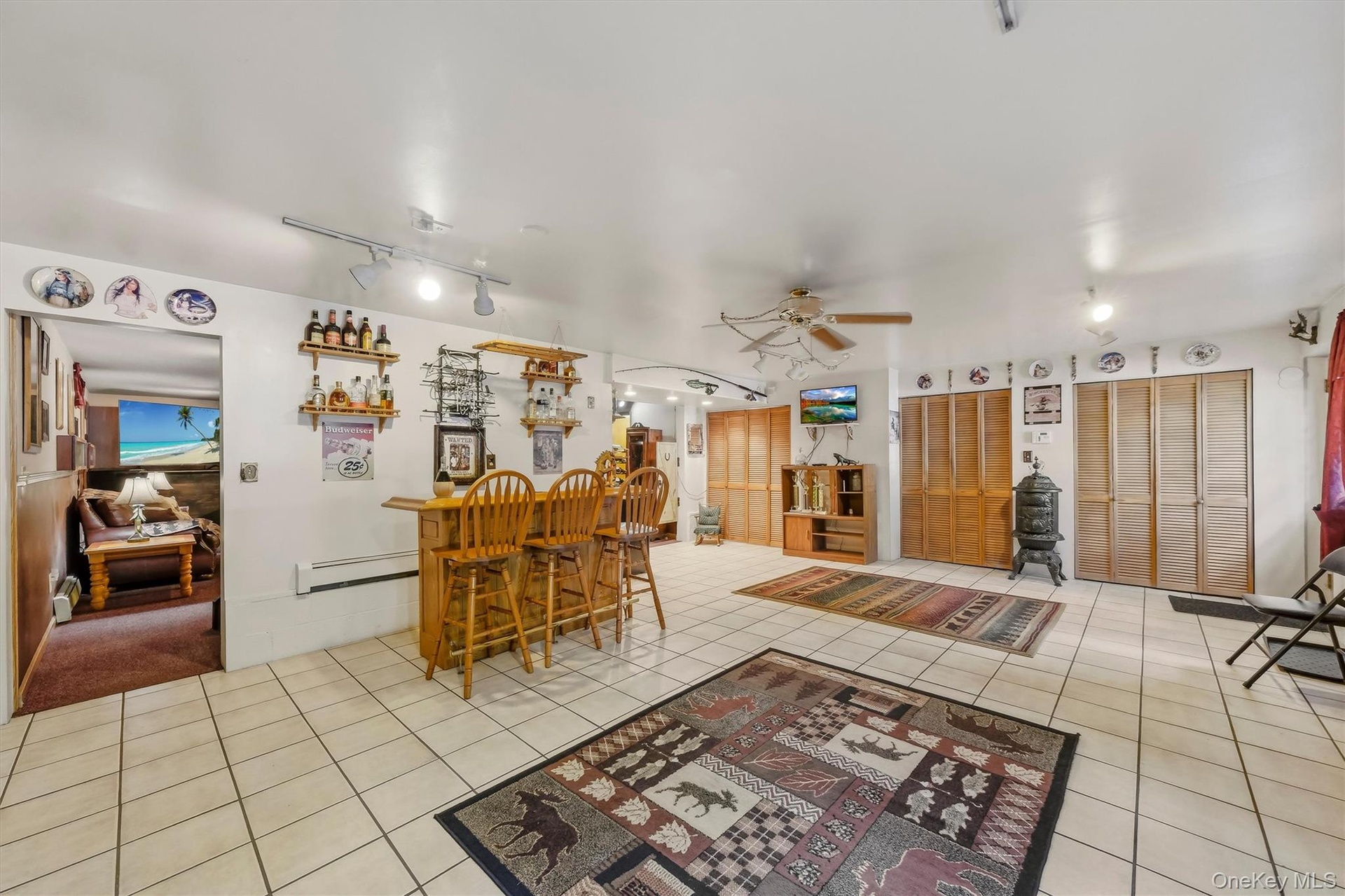 The finished basement features 2 rooms, one a gathering room and the other a bar/play area with tiled floor and an entrance to the driveway.