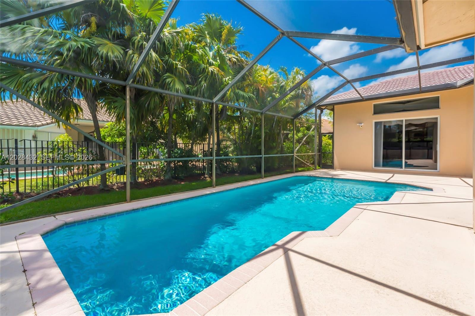 Open-concept interior featuring recessed lighting, large-format tile flooring, and oversized glass sliding doors leading to a screened-in lanai