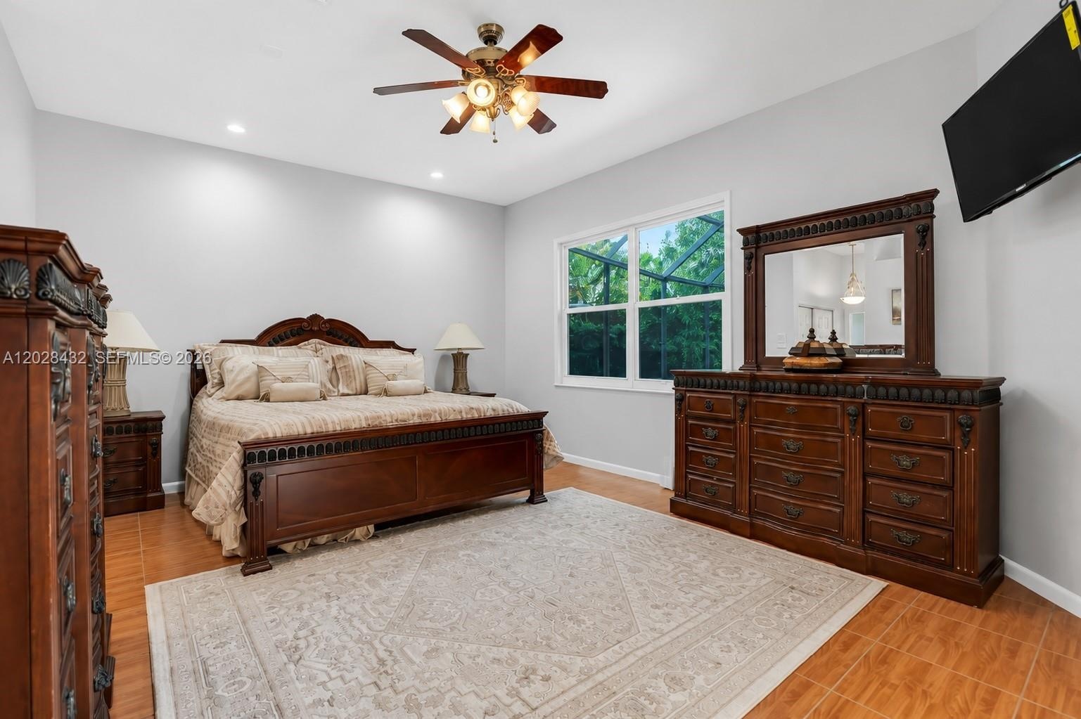 Room featuring dual arched windows, tile flooring, and a ceiling fan with integrated lighting