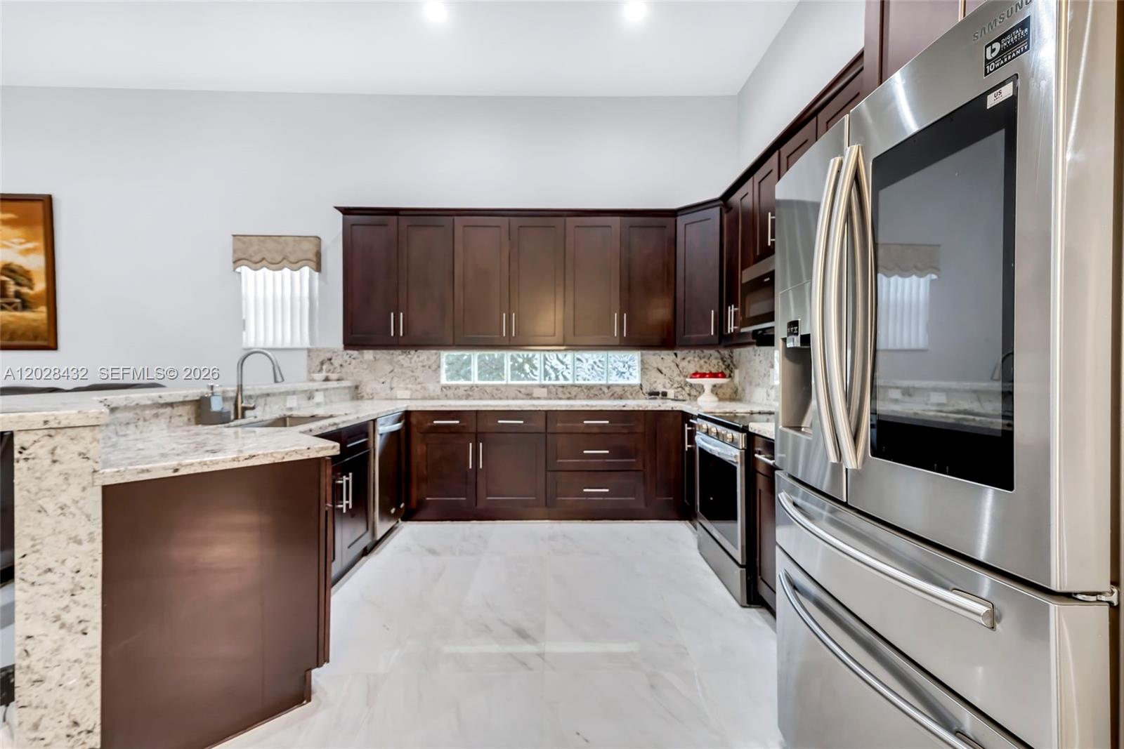 Open-concept interior featuring polished tile flooring, recessed lighting, expansive glass sliding doors, and architectural columns framing an arched 