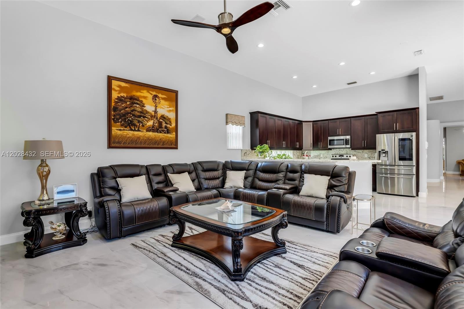 Neutral wall tones, large arched windows, neutral tile flooring, and a multi-blade ceiling fan with integrated lighting