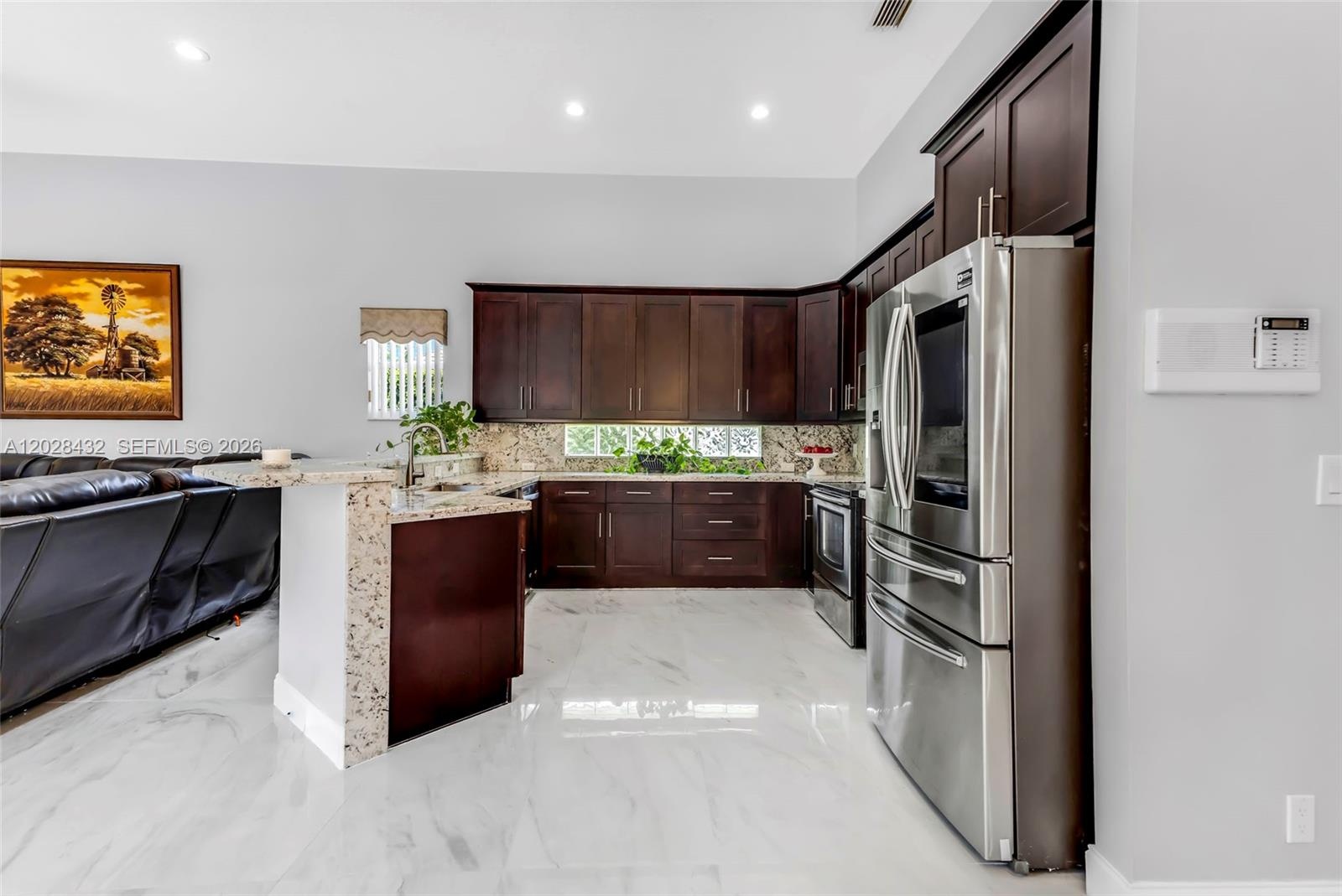 Open-concept living space featuring high ceilings, recessed lighting, a modern ceiling fan, tile flooring, and dark wood-finish cabinetry