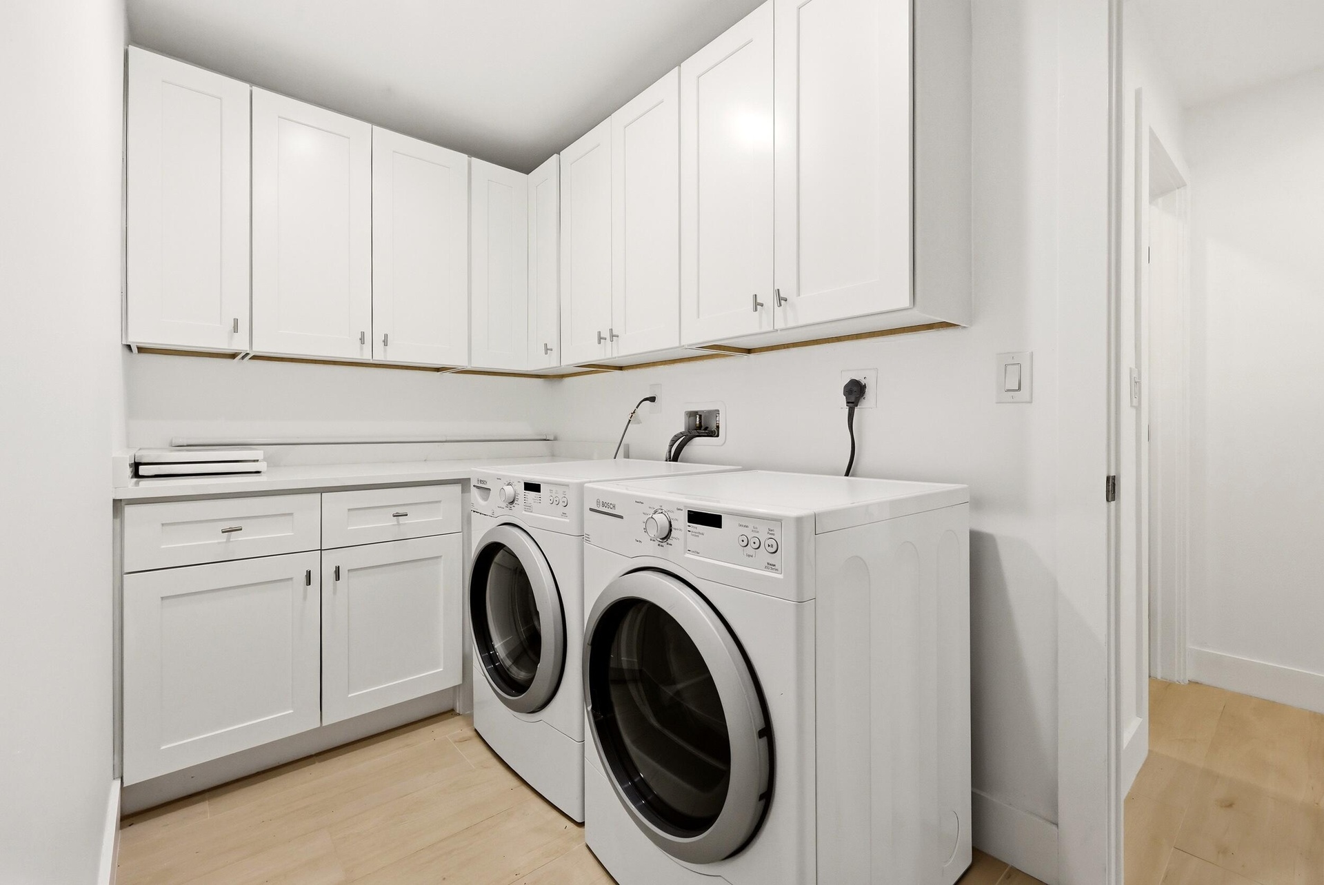 Thoughtfully designed for everyday convenience, the spacious laundry room features abundant custom cabinetry, extensive countertop workspace for foldi