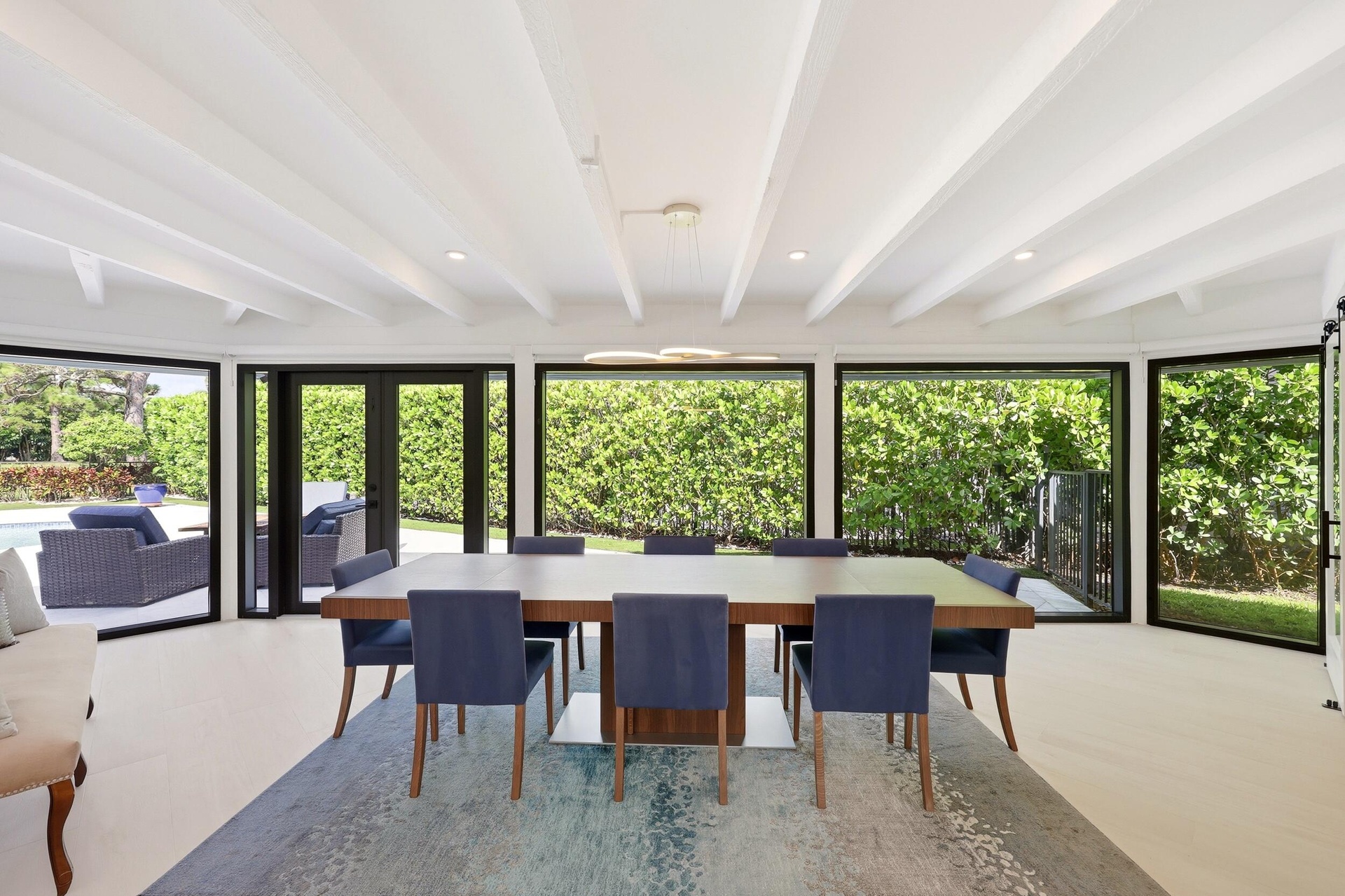 Framed by walls of hurricane impact glass and tranquil views of the pool and lush preserve beyond, the dining room offers an unforgettable setting for
