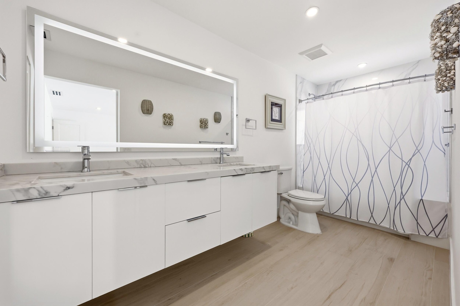 Beautifully updated with a sleek contemporary design, this spacious guest bathroom features an oversized floating vanity with dual sinks, quartz count