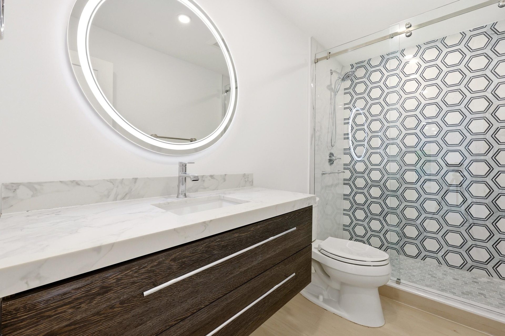 A striking blend of style and sophistication, this beautifully renovated guest bathroom features a custom wood vanity topped with quartz countertops, 