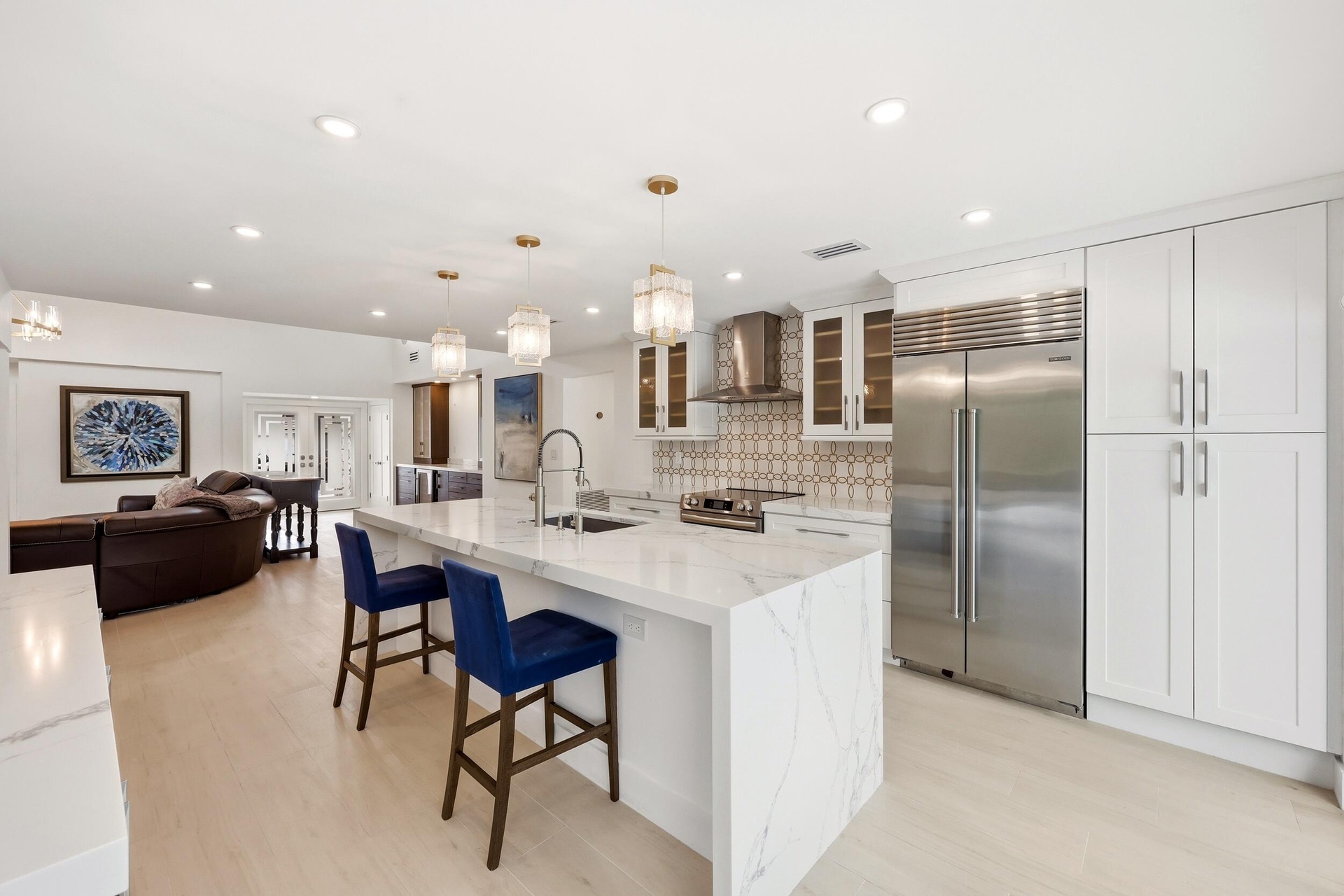 The beautifully renovated chef's kitchen showcases timeless white cabinetry, warm brushed gold accents, Carrara quartz countertops, and premium applia
