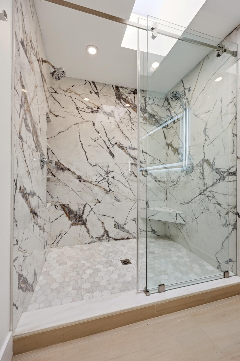 The spa-inspired primary bath showcases a sleek floating dual-sink vanity with quartz countertops, an illuminated designer mirror, and a stunning over