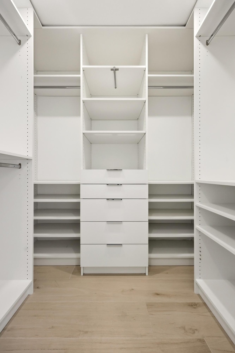 The custom walk-in closet is thoughtfully designed with extensive built-in storage, adjustable shelving, multiple hanging areas, and dedicated drawer 