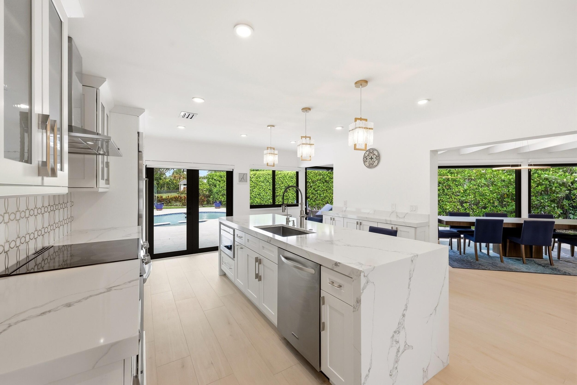 The beautifully renovated chef's kitchen showcases timeless white cabinetry, warm brushed gold accents, Carrara quartz countertops, and premium applia
