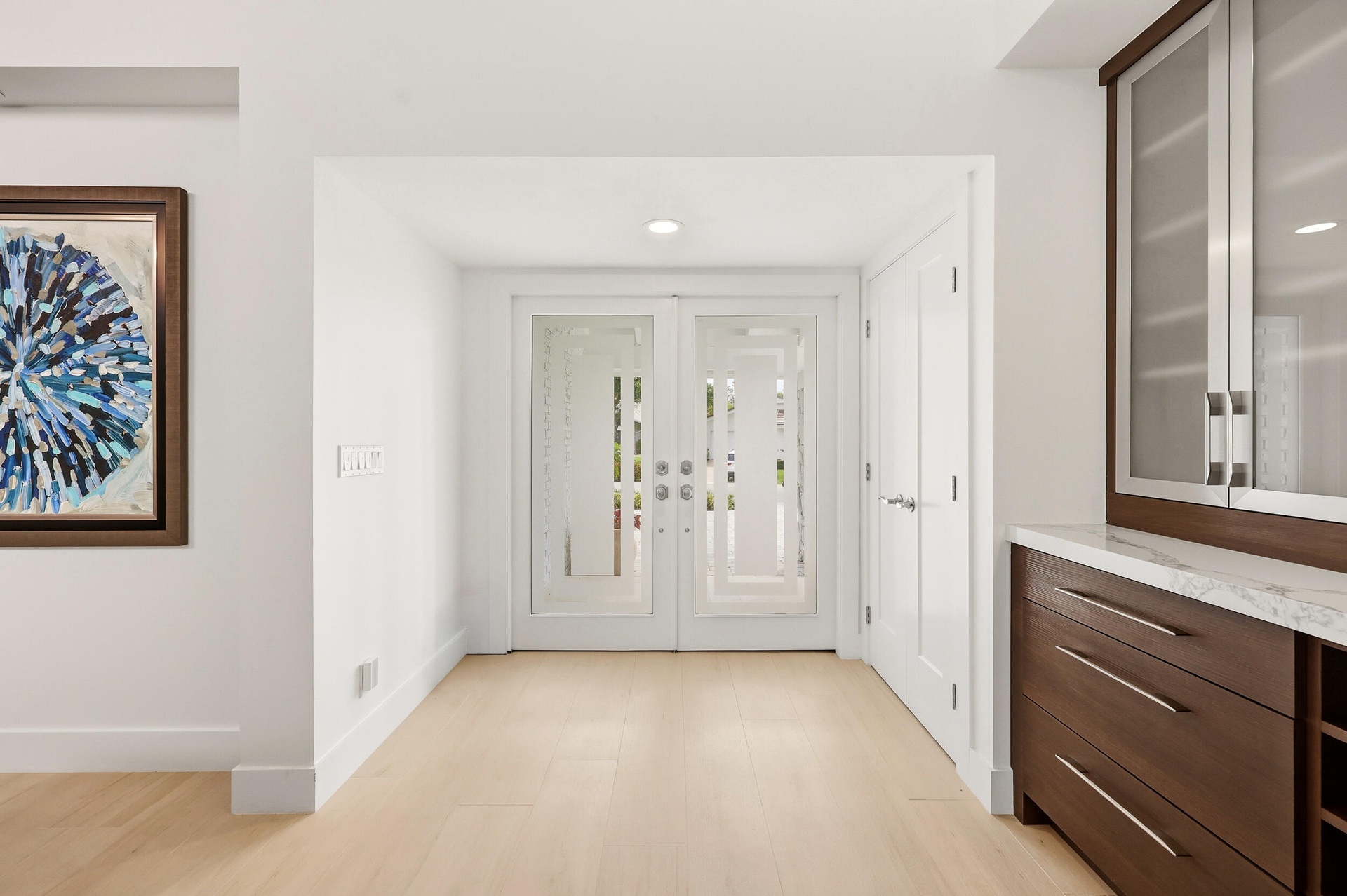 Step inside to a stunning foyer where soaring ceilings, abundant natural light, and wide plank white oak porcelain tile flooring create an unforgettab