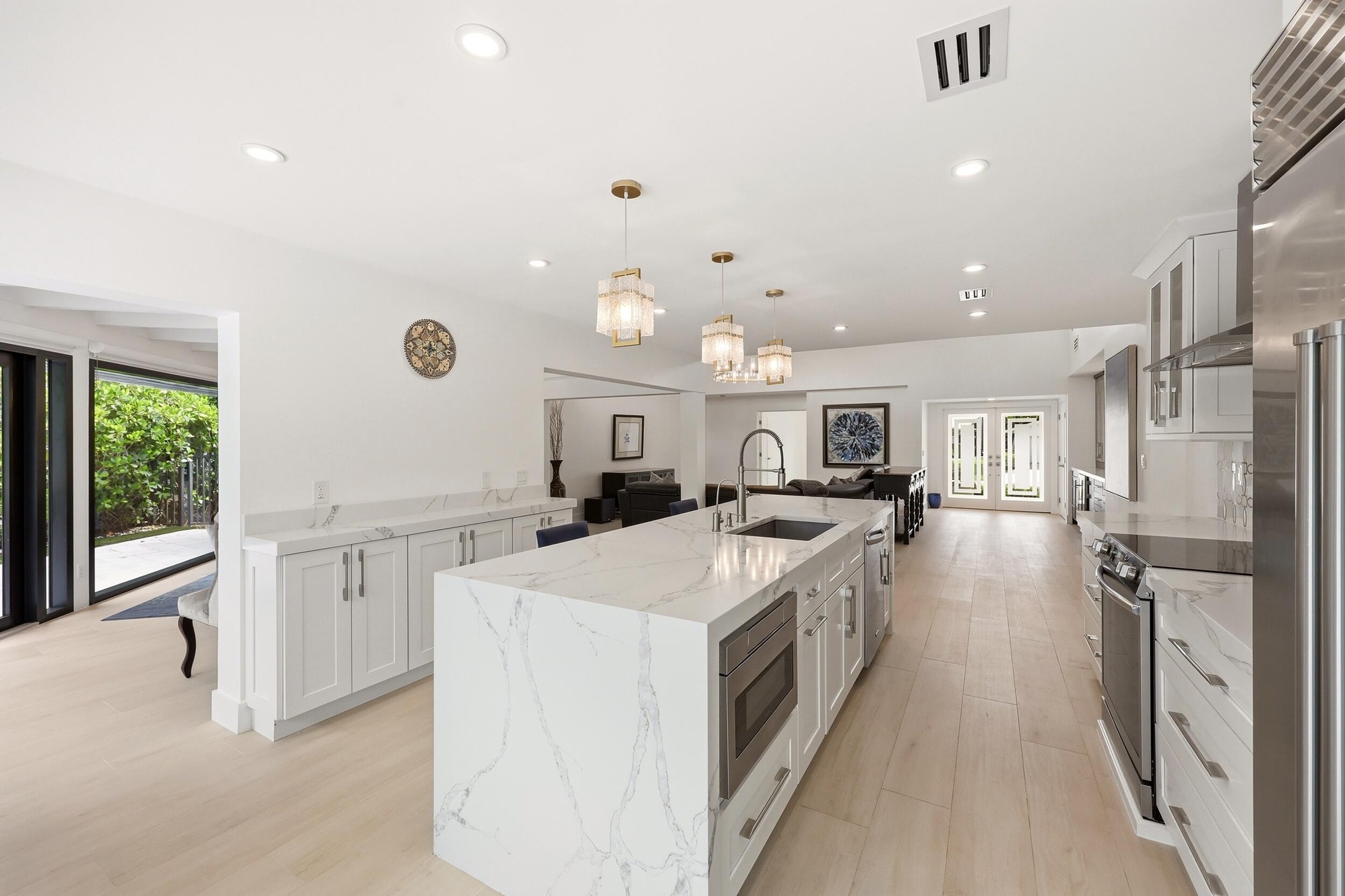 The beautifully renovated chef's kitchen showcases timeless white cabinetry, warm brushed gold accents, Carrara quartz countertops, and premium applia