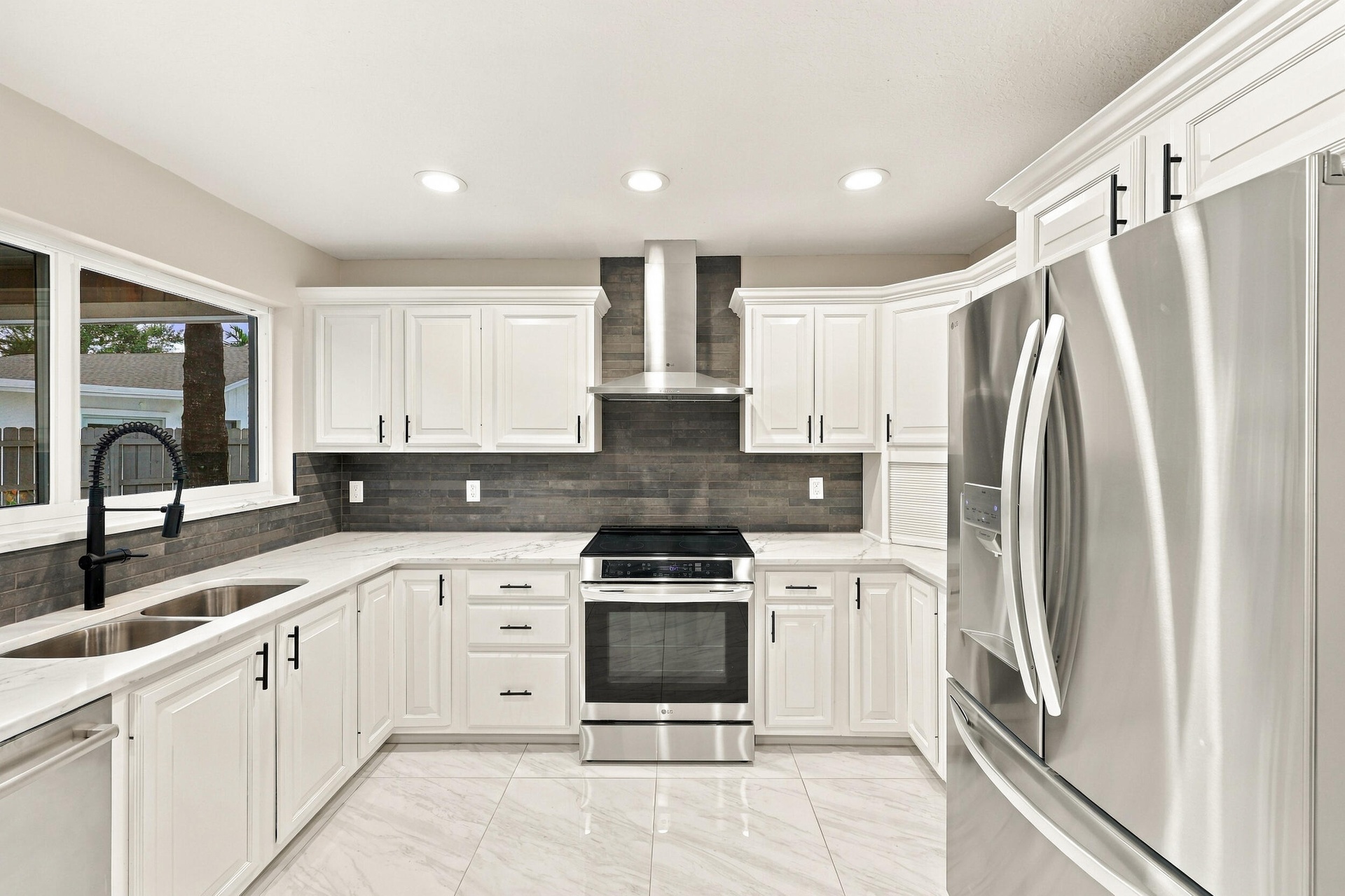 The impeccably upgraded kitchen offers white cabinetry, quartz countertops, stainless steel appliances, and a beautiful charcoal backsplash. There is 