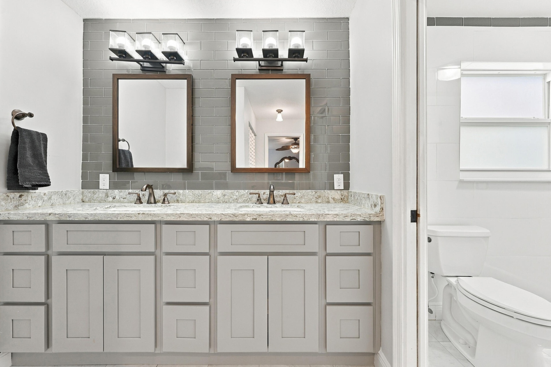 The fully renovated primary bathroom offers dual sinks, updated cabinetry, and a brand-new frameless glass shower.