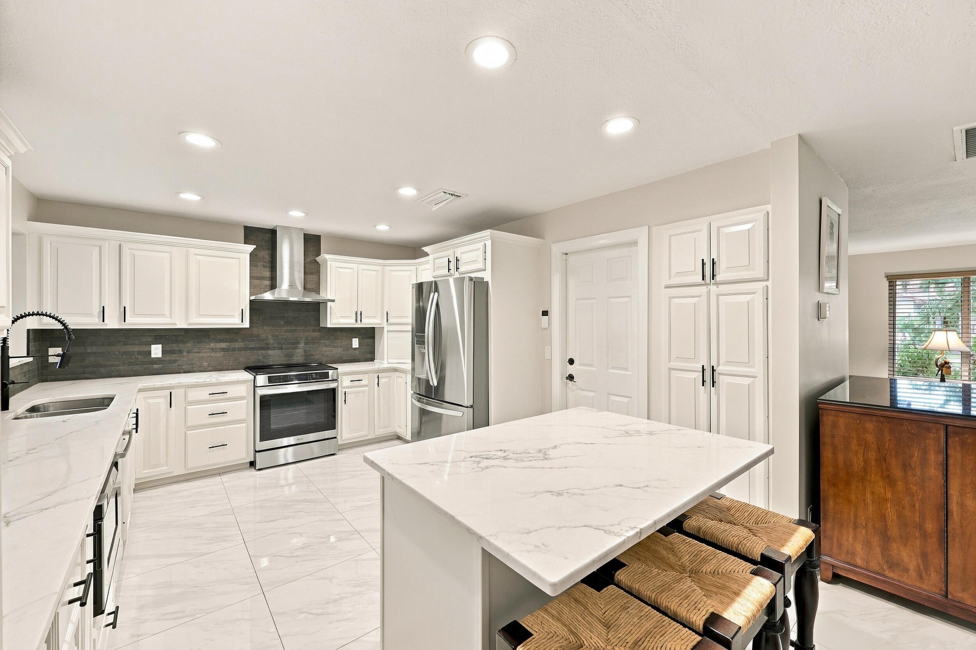 The impeccably upgraded kitchen offers white cabinetry, quartz countertops, stainless steel appliances, and a beautiful charcoal backsplash. There is 