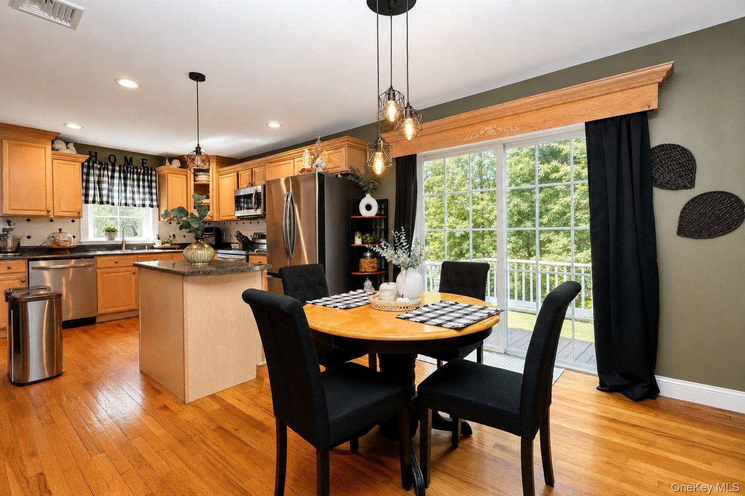 Kitchen featuring  stainless steel appliances, a center island with countertop, wood-finish flooring and sliders to the rear pool area