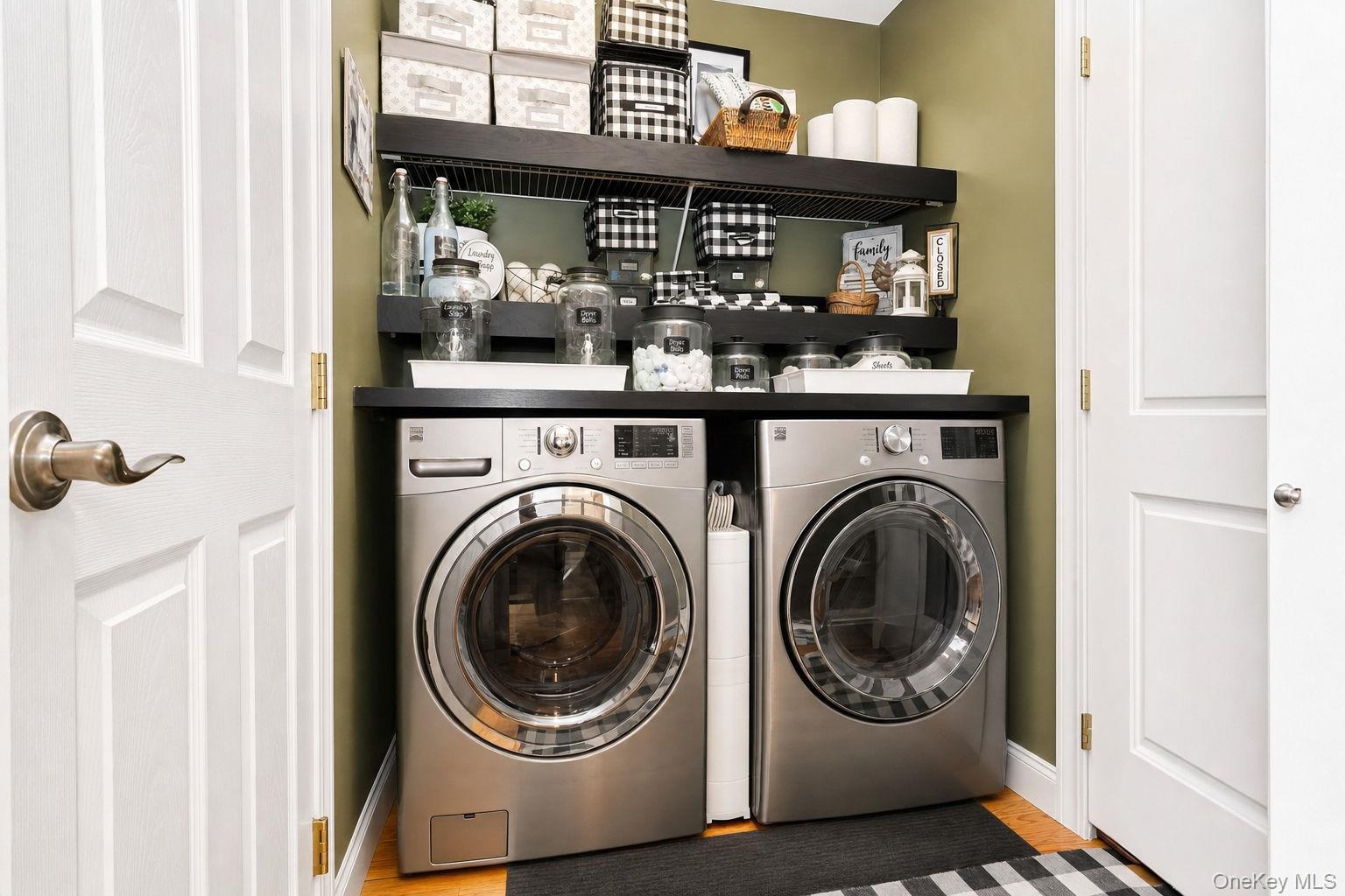 Front-load laundry appliances with a dark countertop and integrated shelving