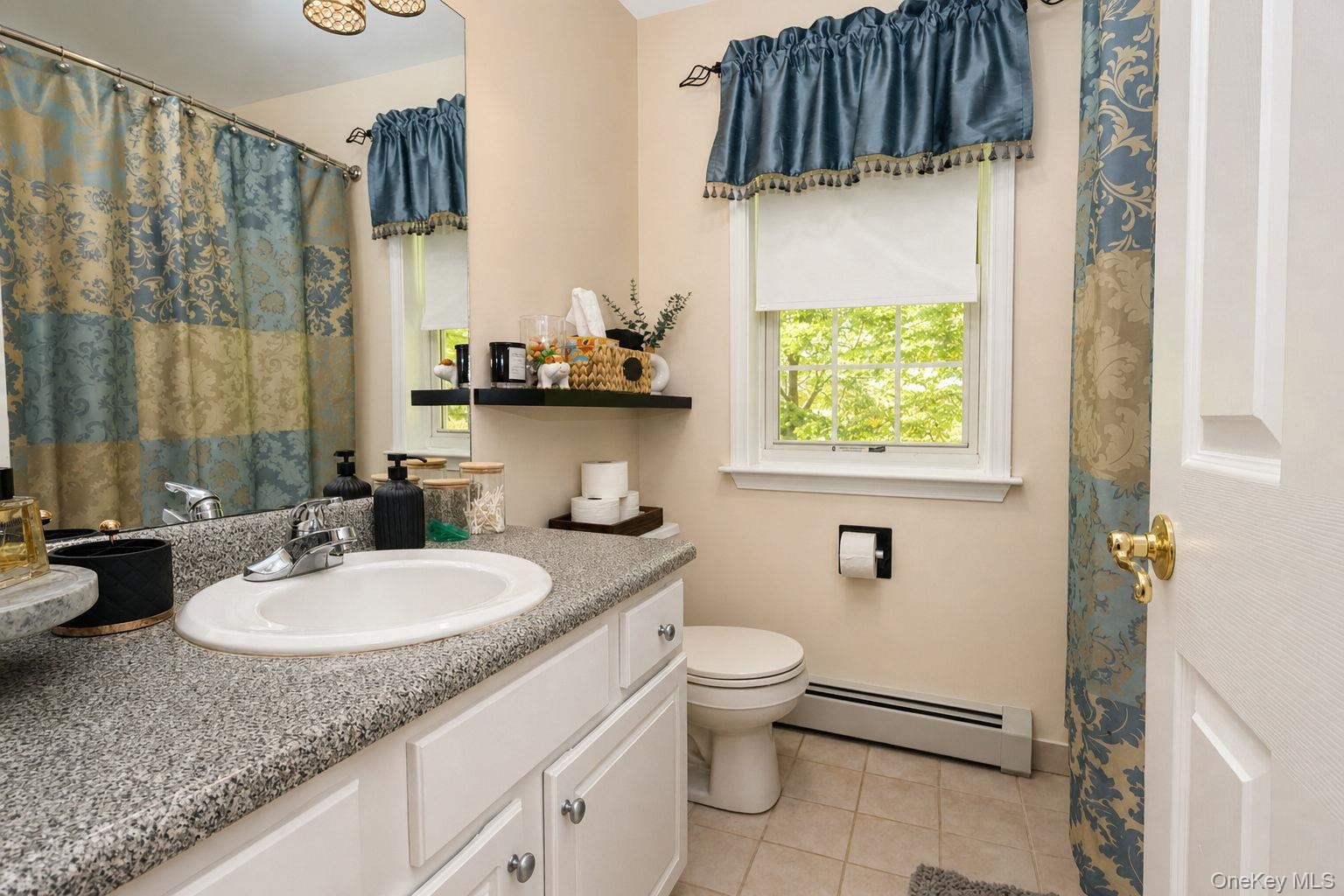 White vanity with under-sink storage, speckled countertop, and a single basin sink