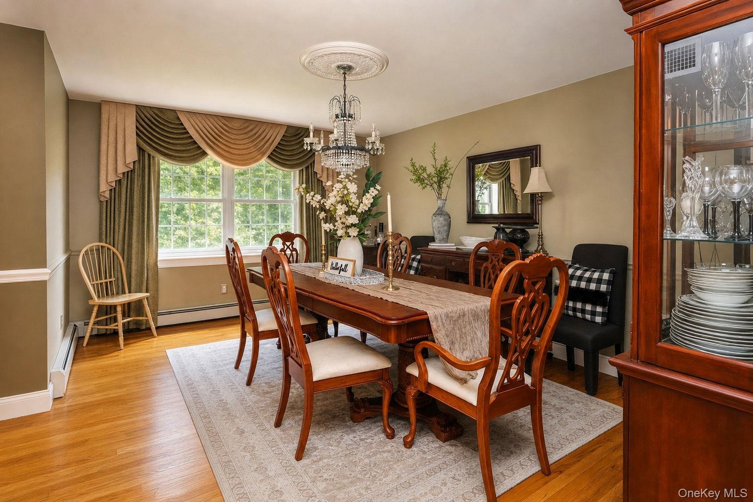 Hardwood flooring, chandelier with ceiling medallion, large window with decorative valance, built-in display cabinet