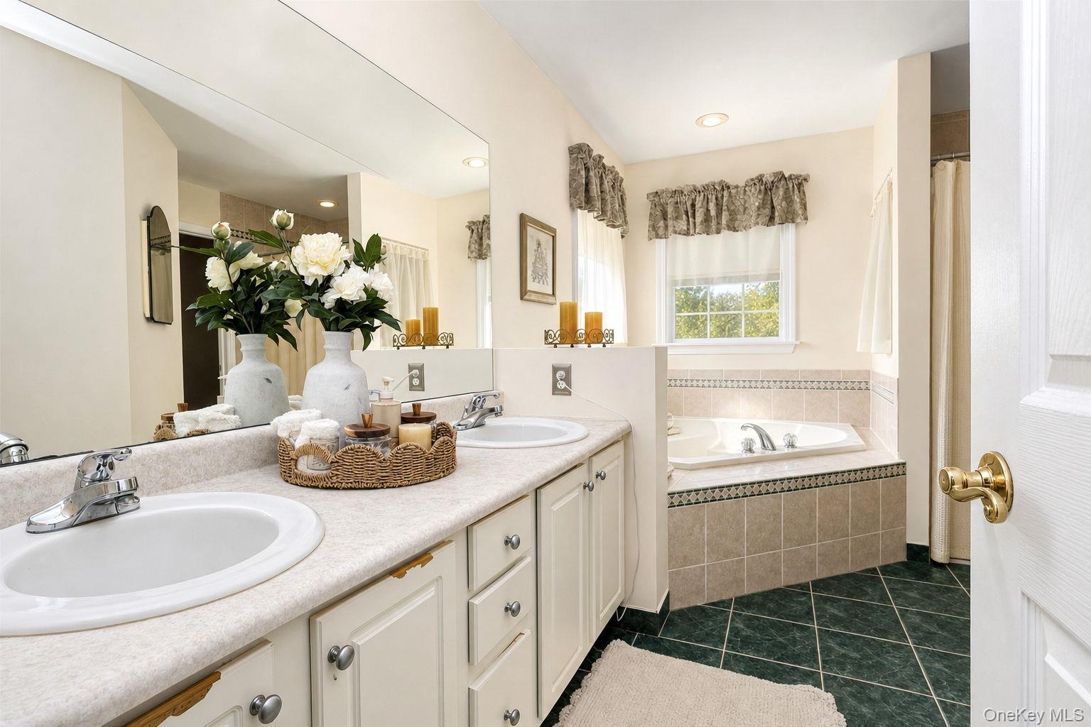 Dual vanity with integrated sinks, a built-in jetted tub, tiled tub surround, separate shower and private toilet room