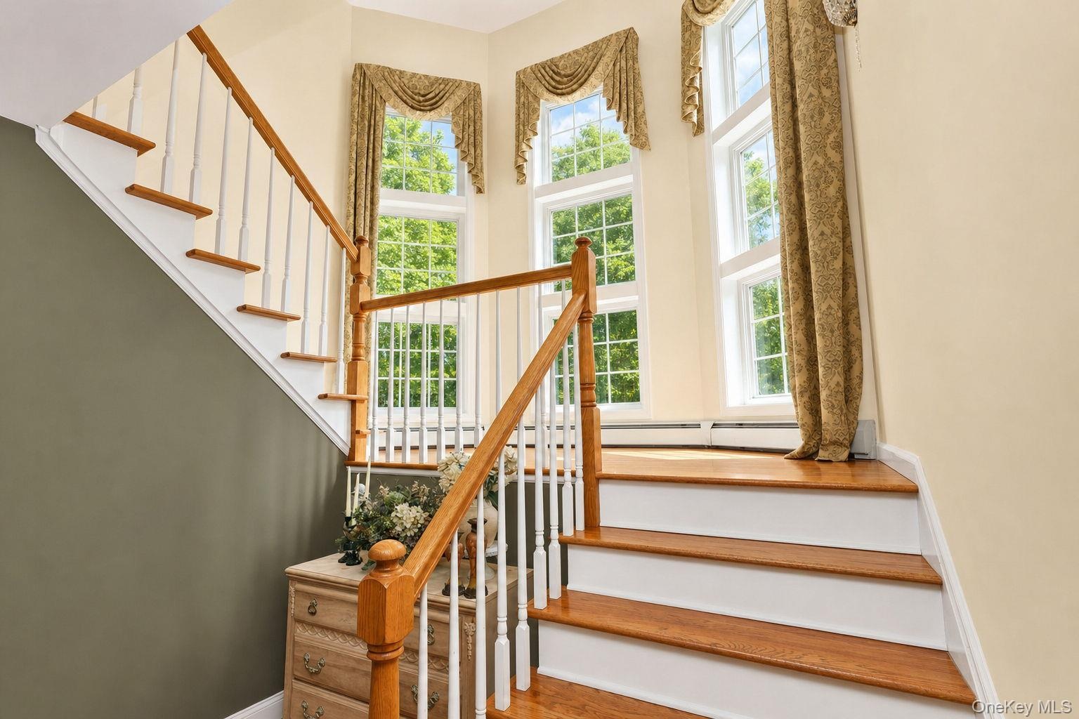 Hardwood staircase with white risers, balusters, landing and wall of windows