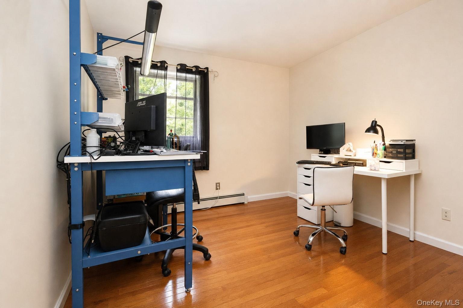 Hardwood flooring throughout, neutral wall paint, and a window with natural light used as an office