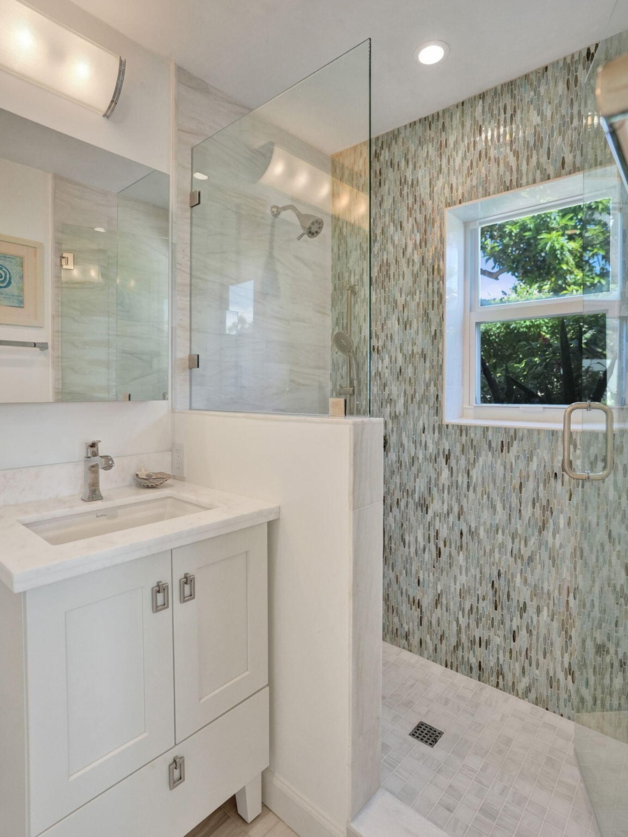 Glass-enclosed shower with mosaic wall tile.