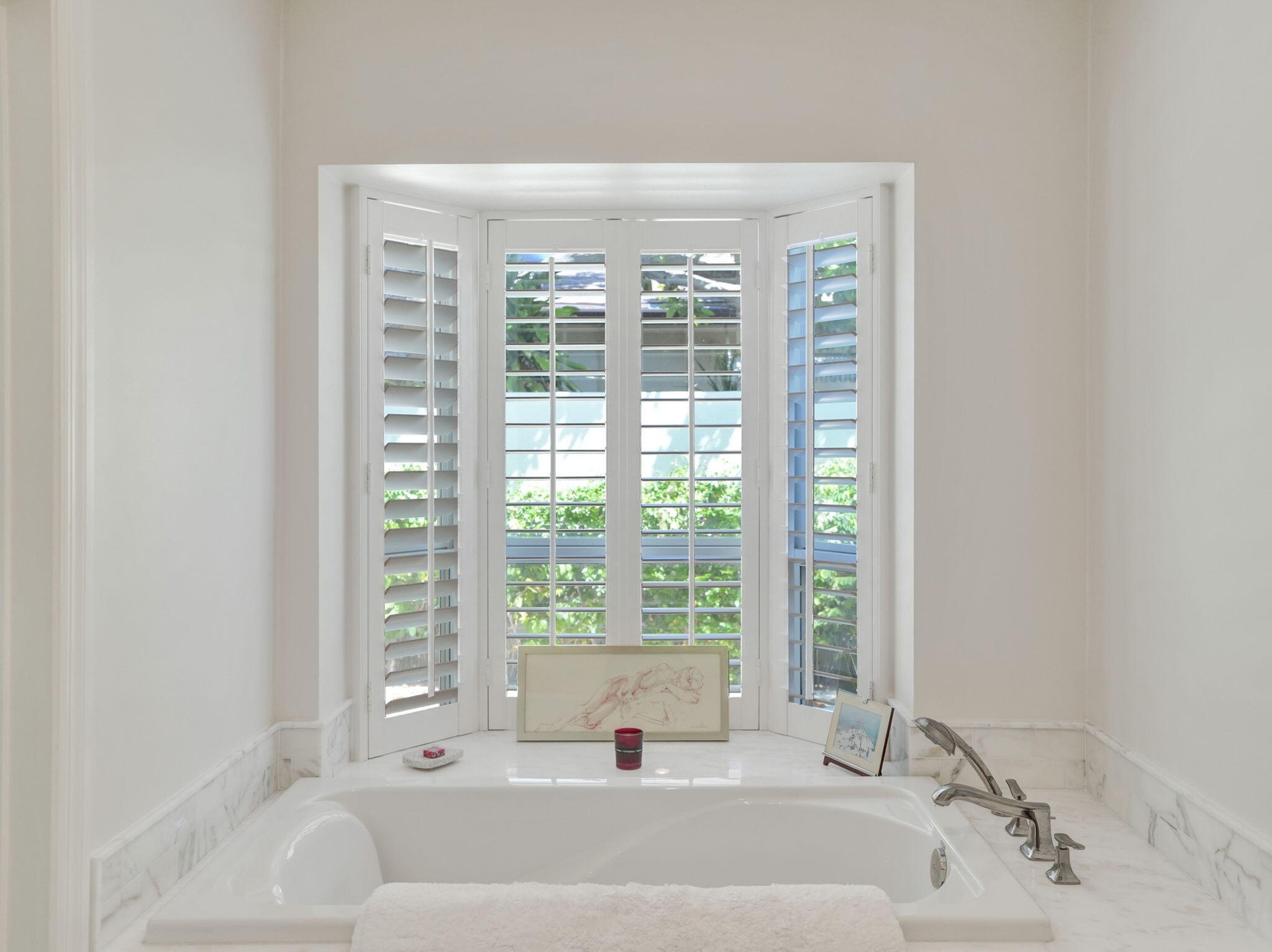 Soaking tub with a polished deck-mounted faucet and handheld shower sprayer, surrounded by a marble-patterned countertop