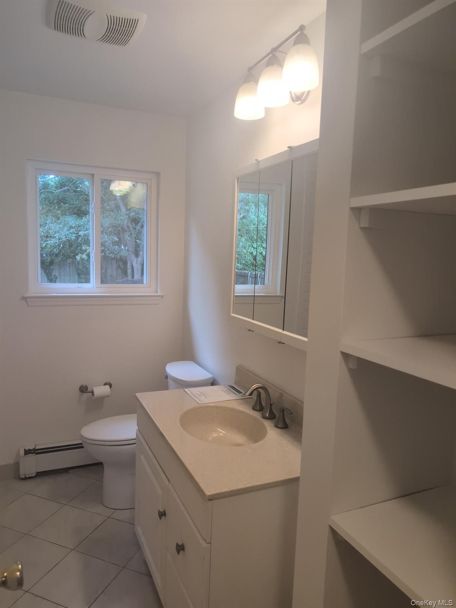 ...linen storage, vanity cabinet, mirror, and newer fan and light fixture.