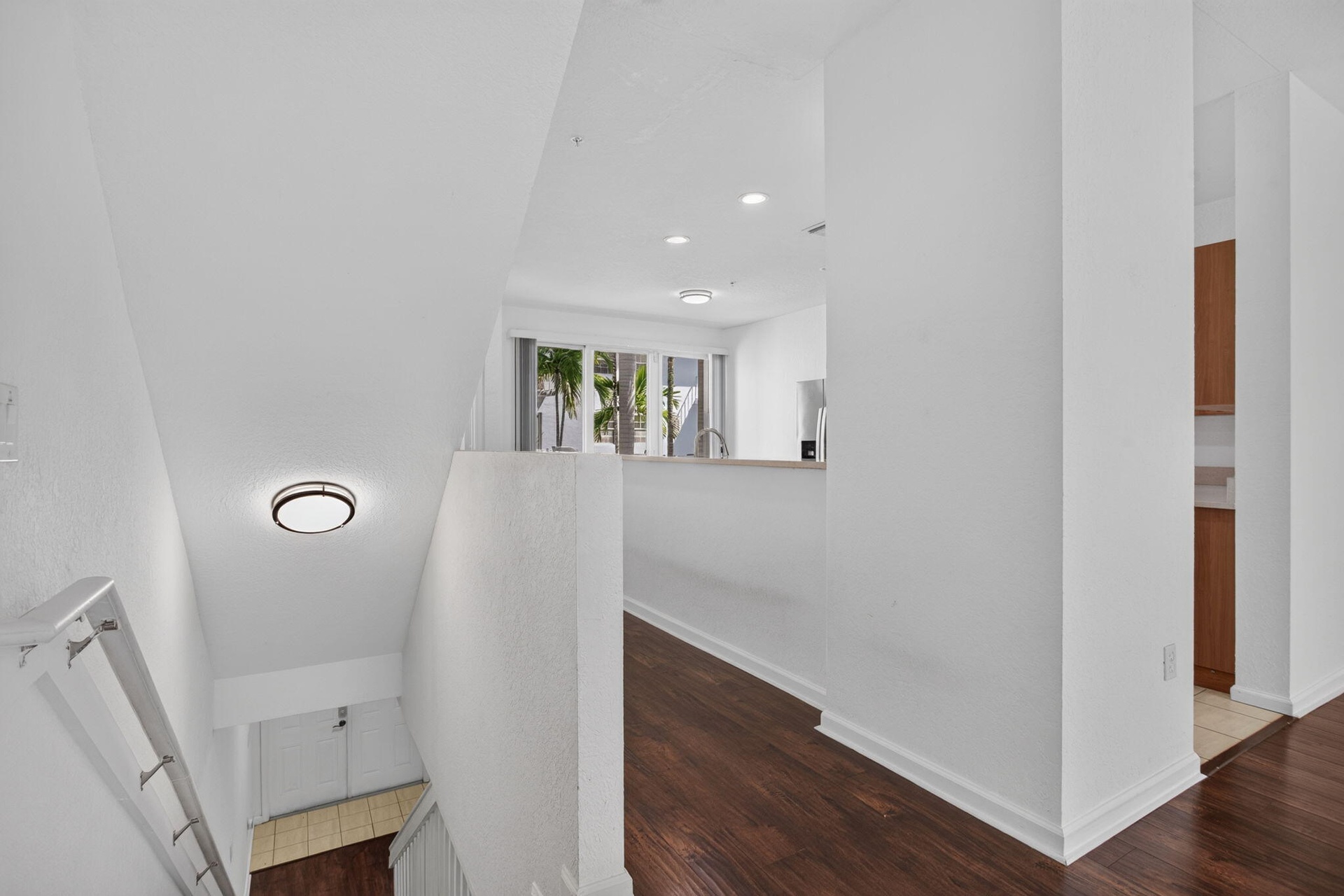 Wood-finish flooring, recessed lighting, and a contemporary flush-mount ceiling fixture