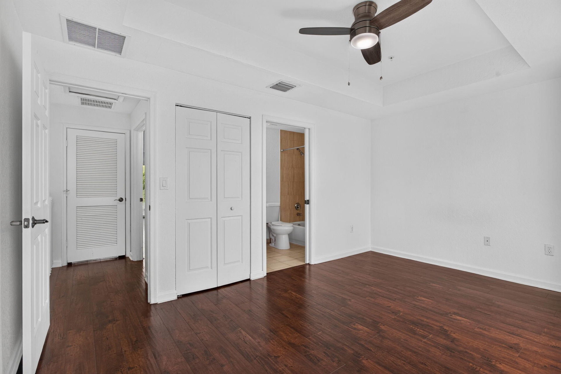 Room featuring wood-finish flooring, a ceiling fan, and tray ceiling