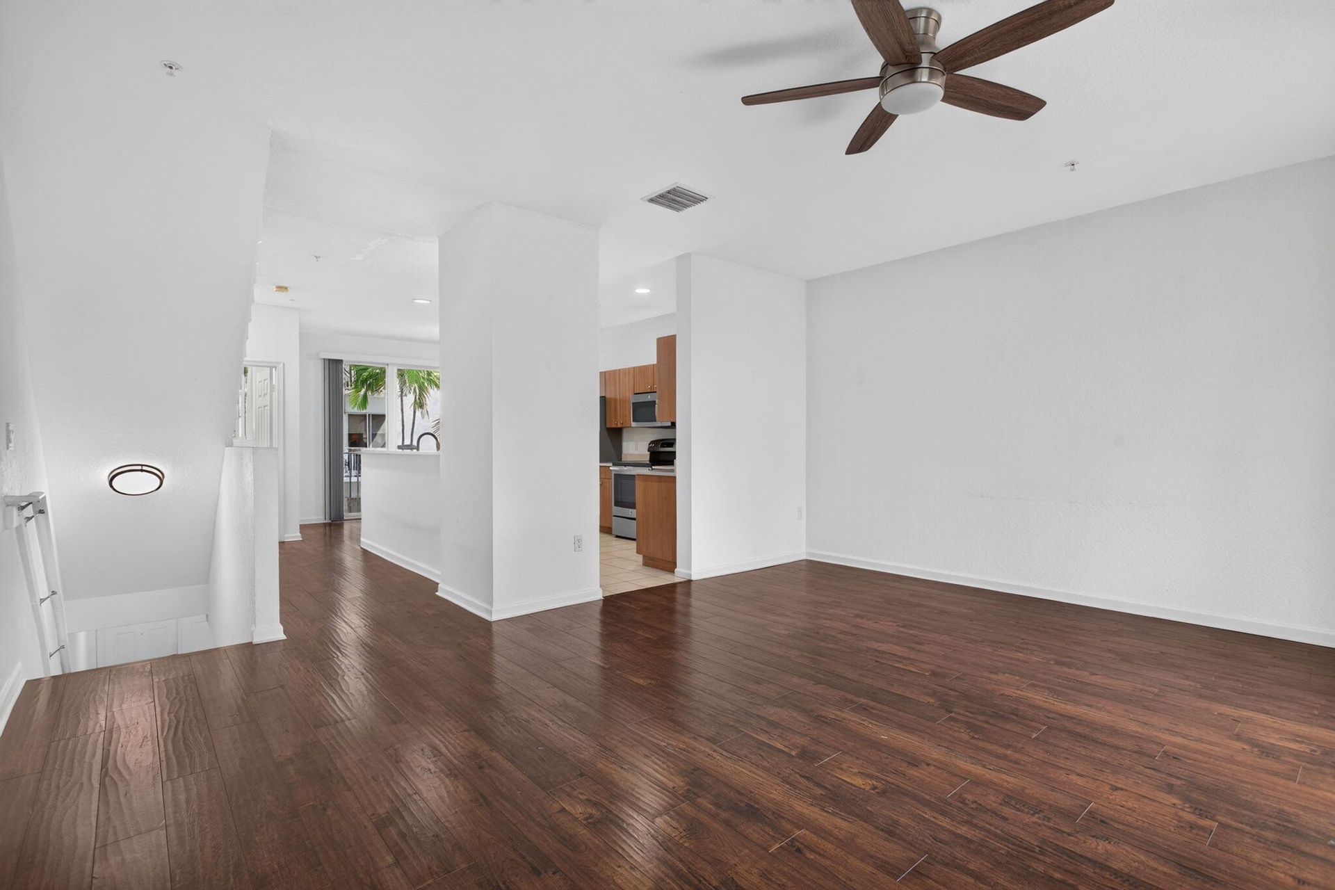 Wood-finish flooring throughout, high ceilings, and a ceiling fan with integrated lighting