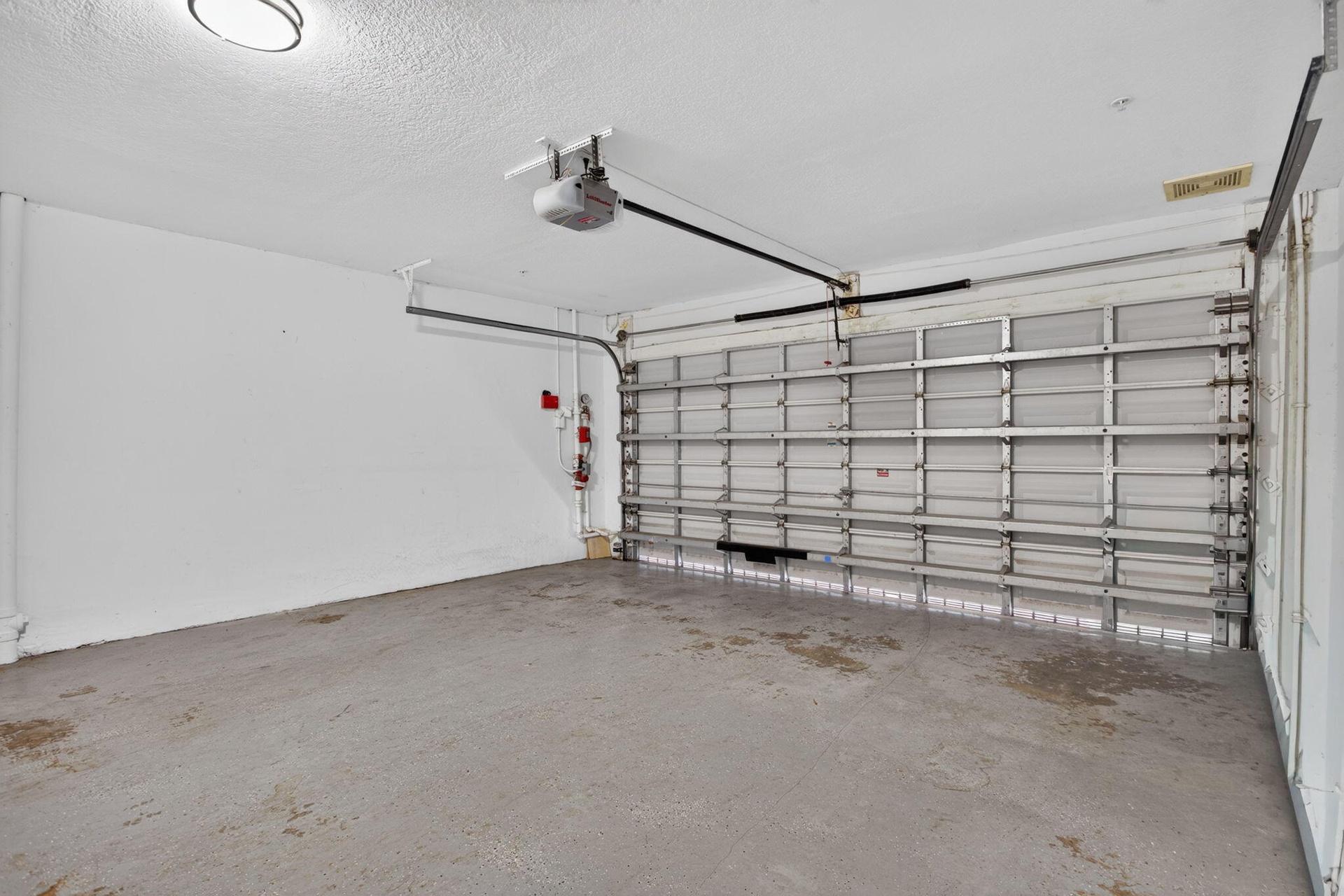Garage with automatic overhead door opener and concrete flooring