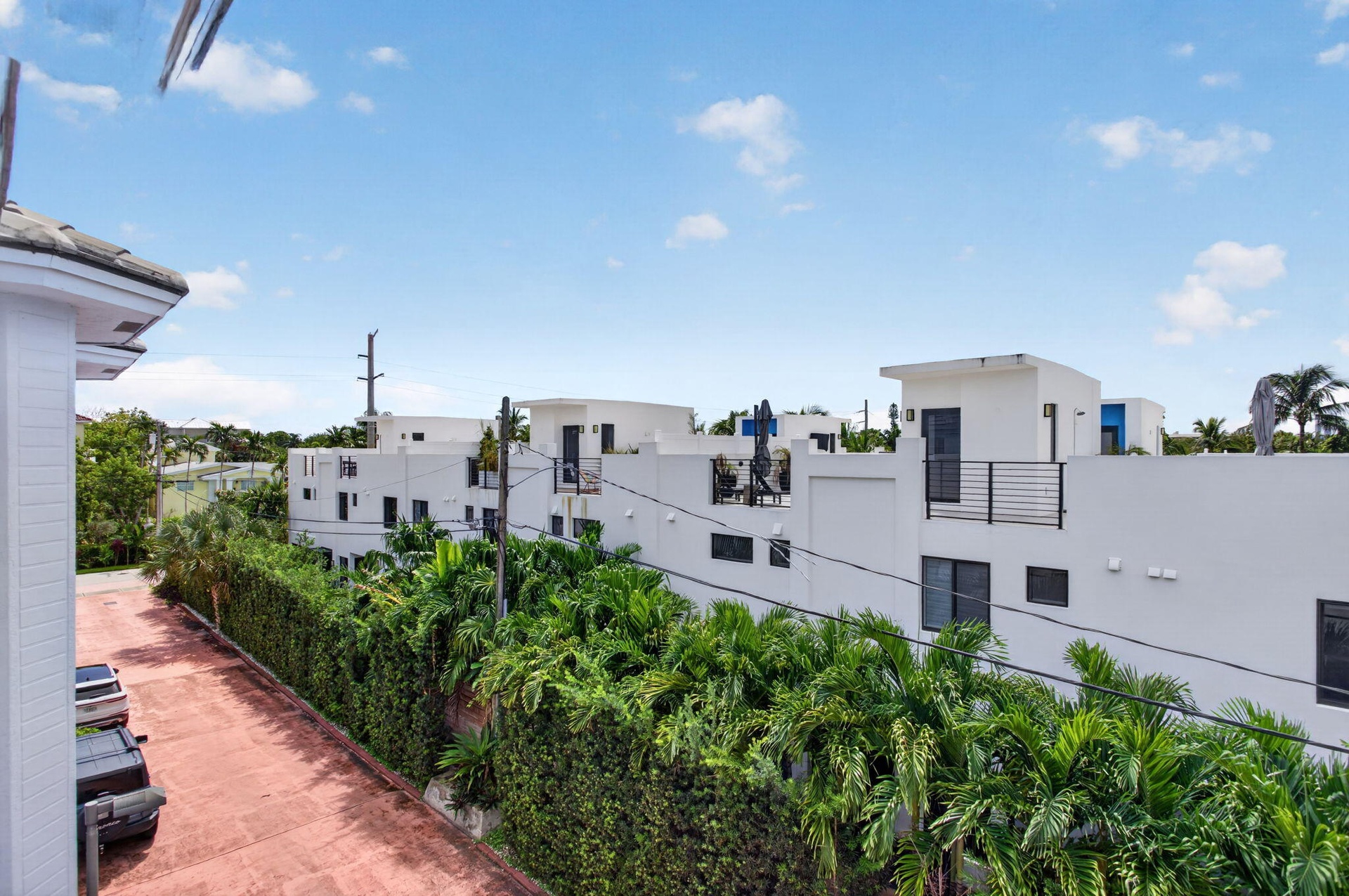 Paved driveway with ample parking, bordered by dense green foliage