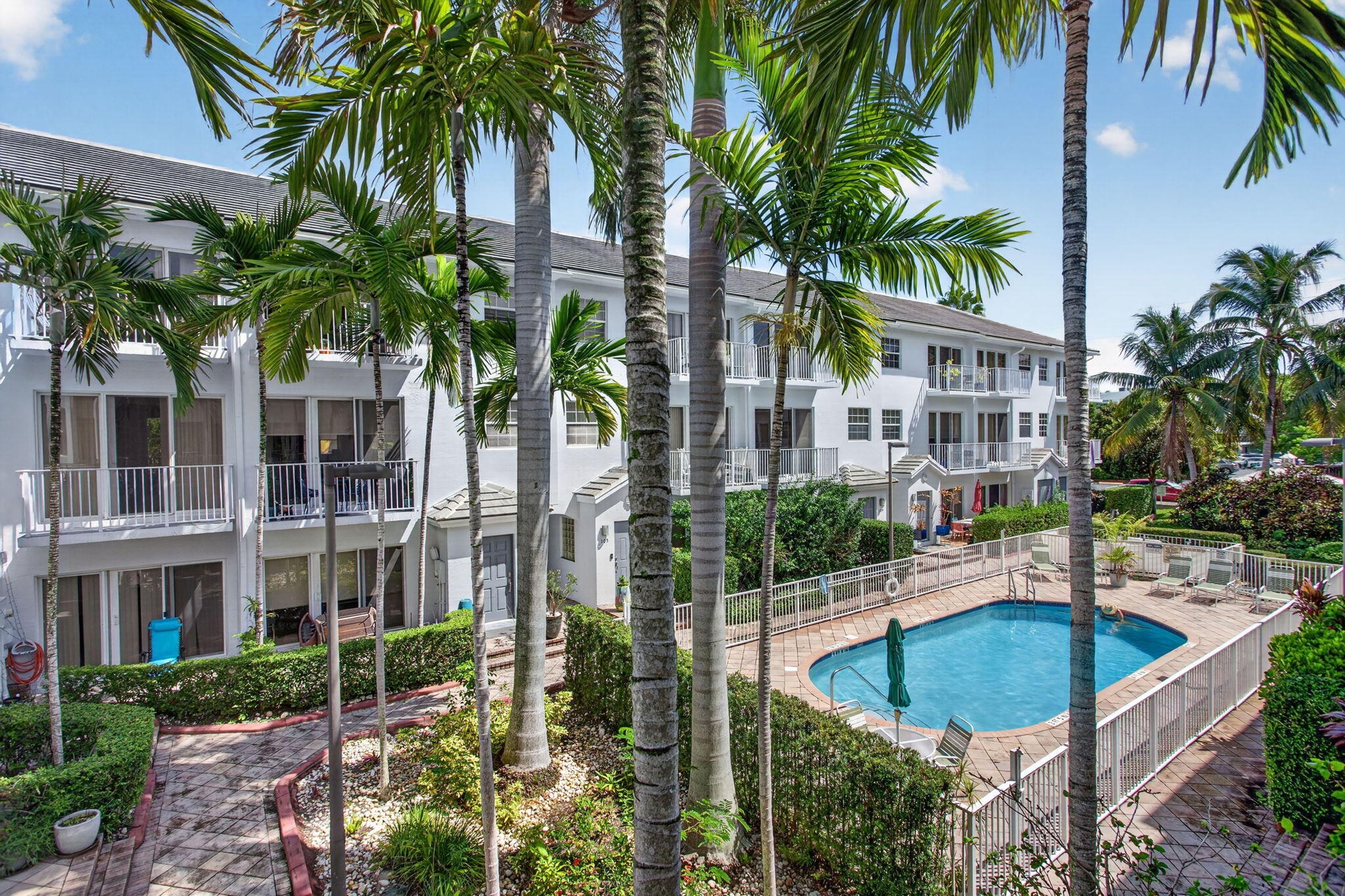 Two-story residences with balconies, a swimming pool with paved decking, and lush landscaping